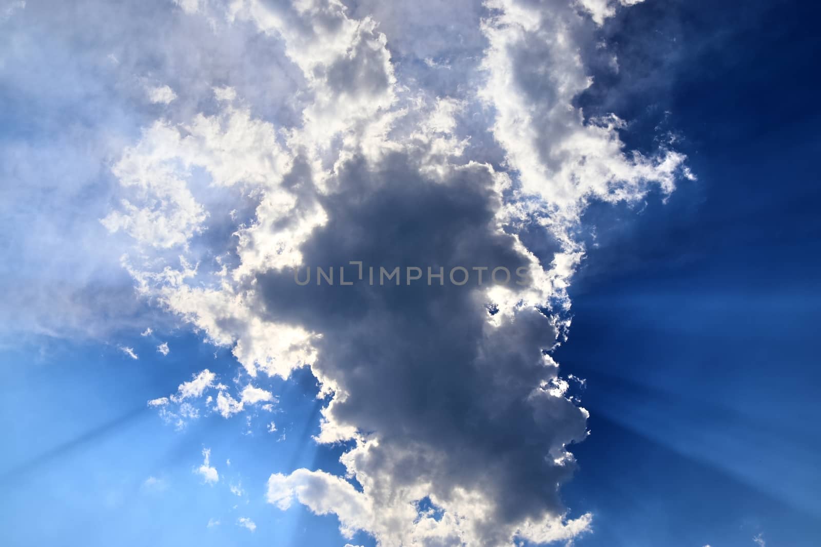 Beautiful view at bright sunbeams with some lens flares and clouds in a blue sky