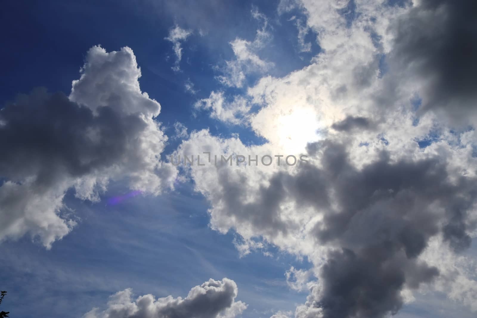 Beautiful view at bright sunbeams with some lens flares and clouds in a blue sky