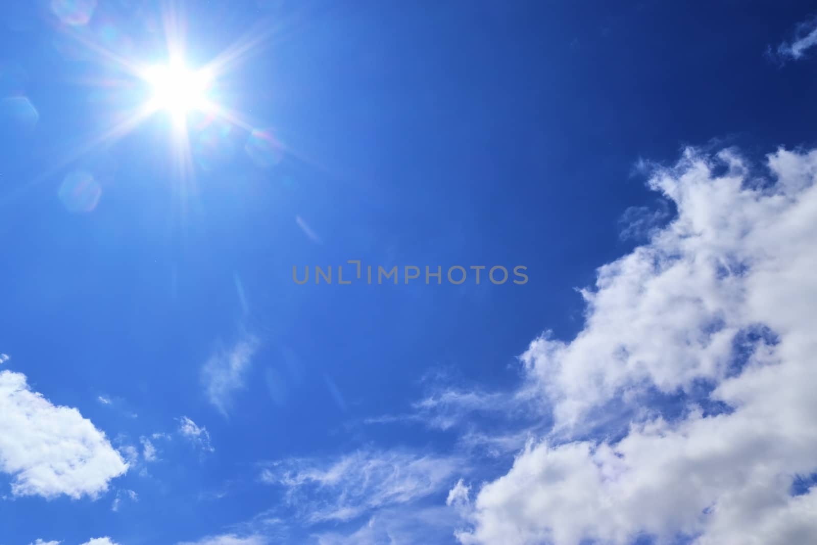 Beautiful view at bright sunbeams with some lens flares and clouds in a blue sky