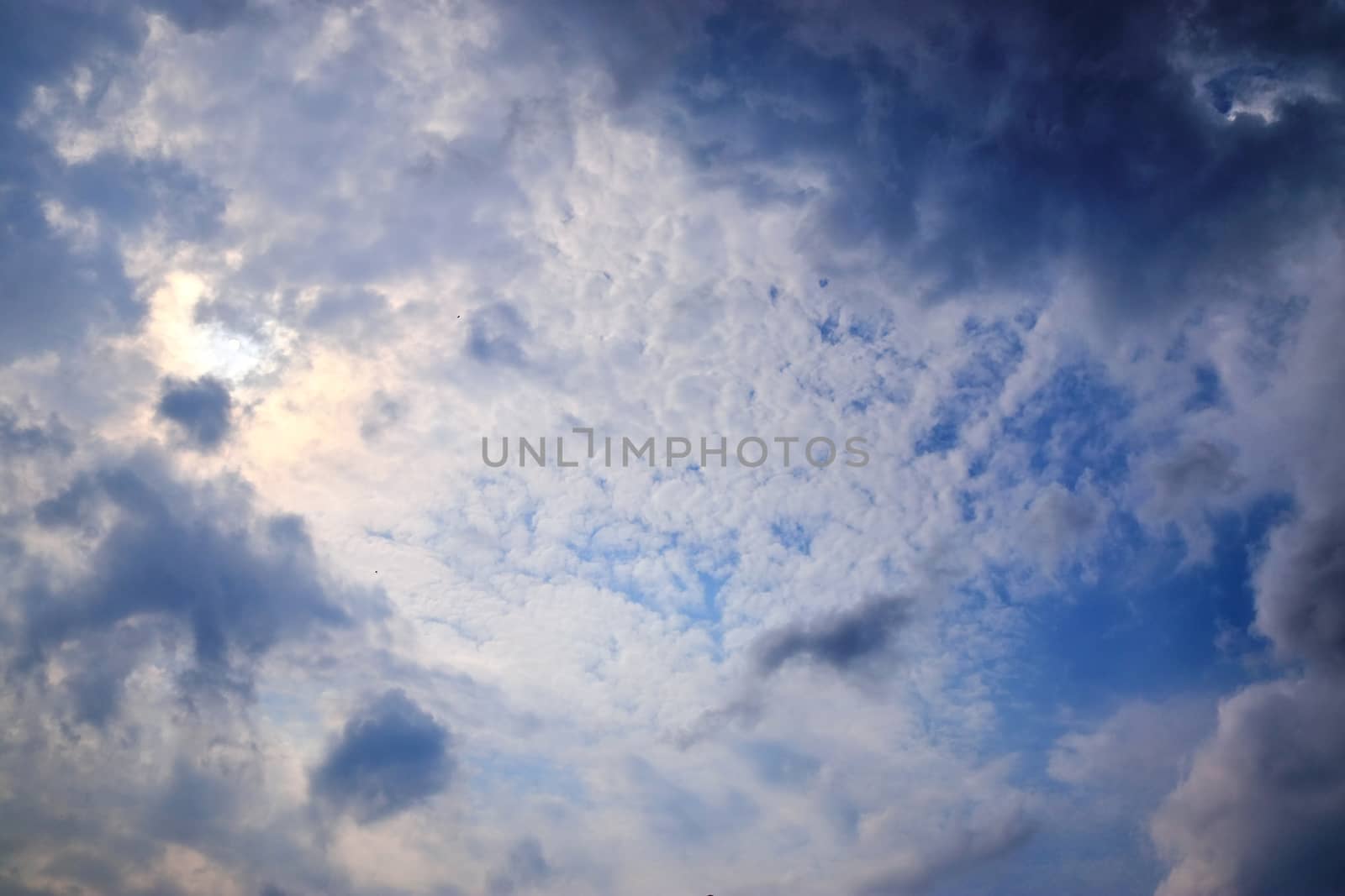 Beautiful view at bright sunbeams with some lens flares and clouds in a blue sky