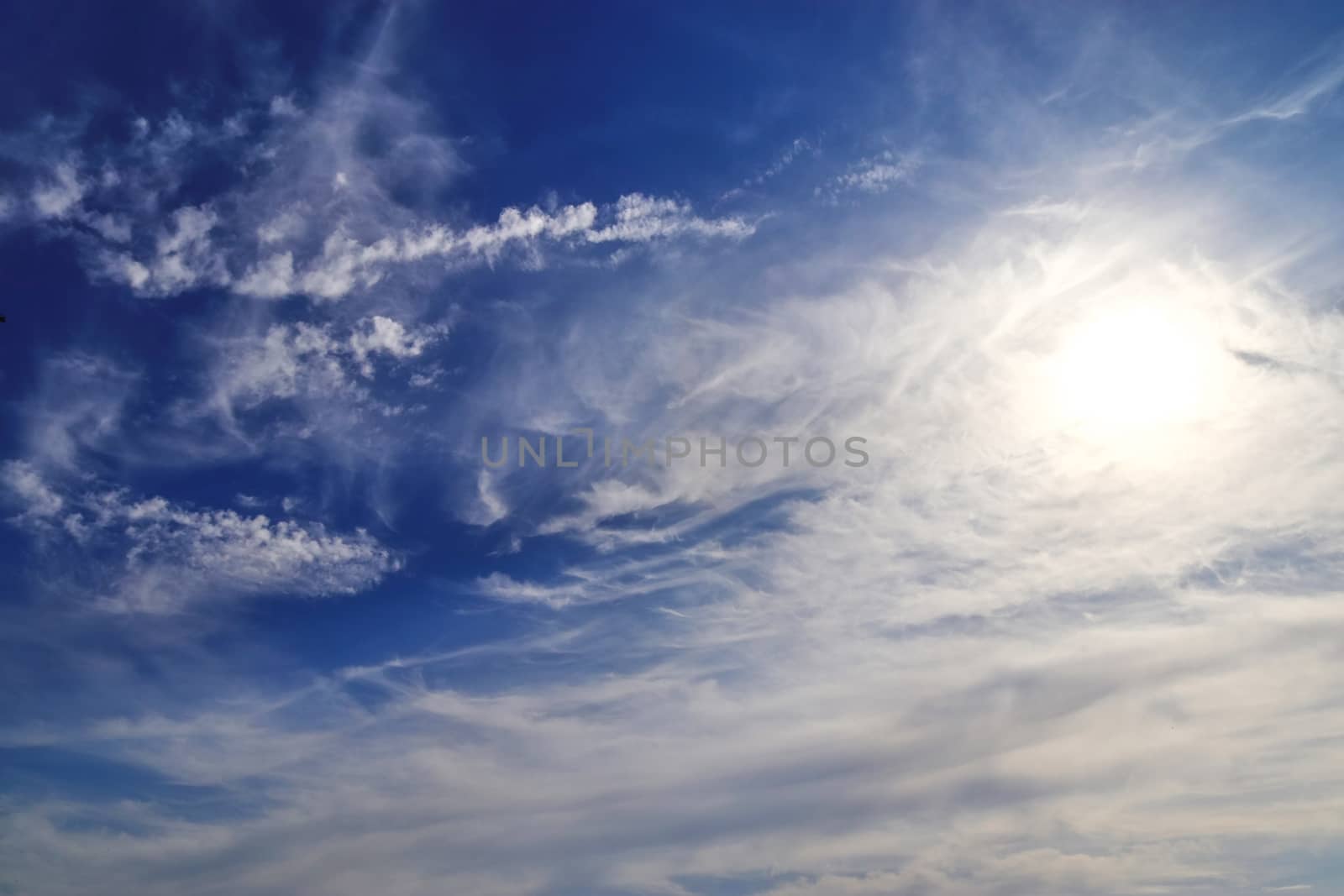 Beautiful view at bright sunbeams with some lens flares and clouds in a blue sky