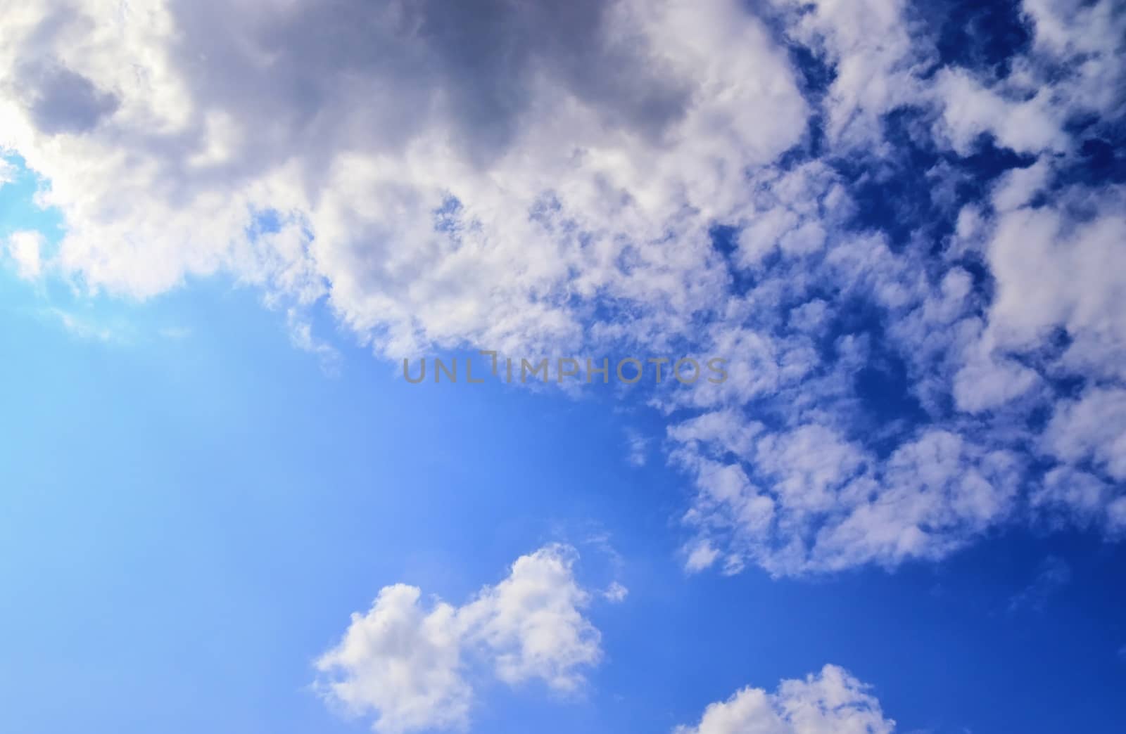 Beautiful view at bright sunbeams with some lens flares and clouds in a blue sky