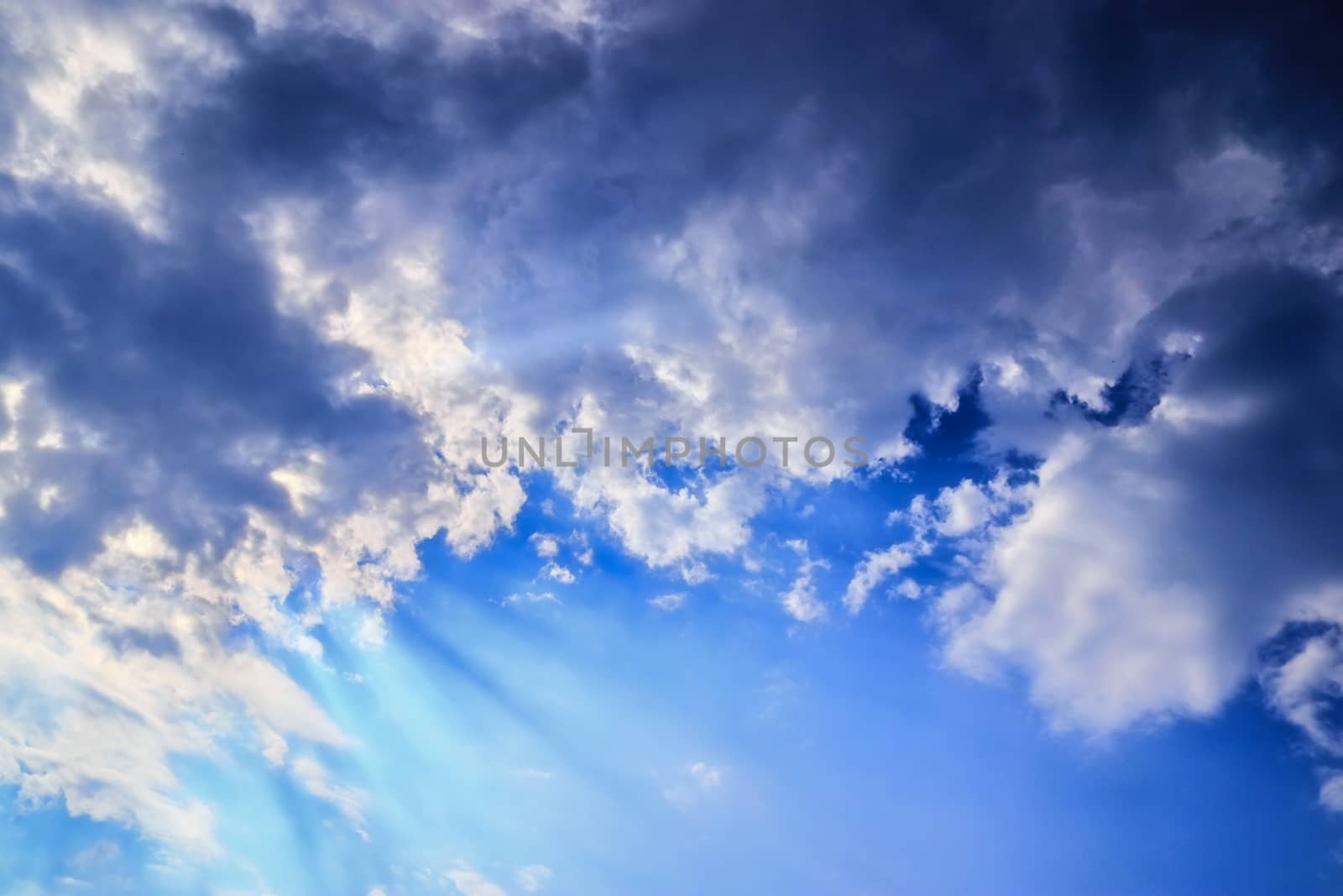 Beautiful view at bright sunbeams with some lens flares and clouds in a blue sky