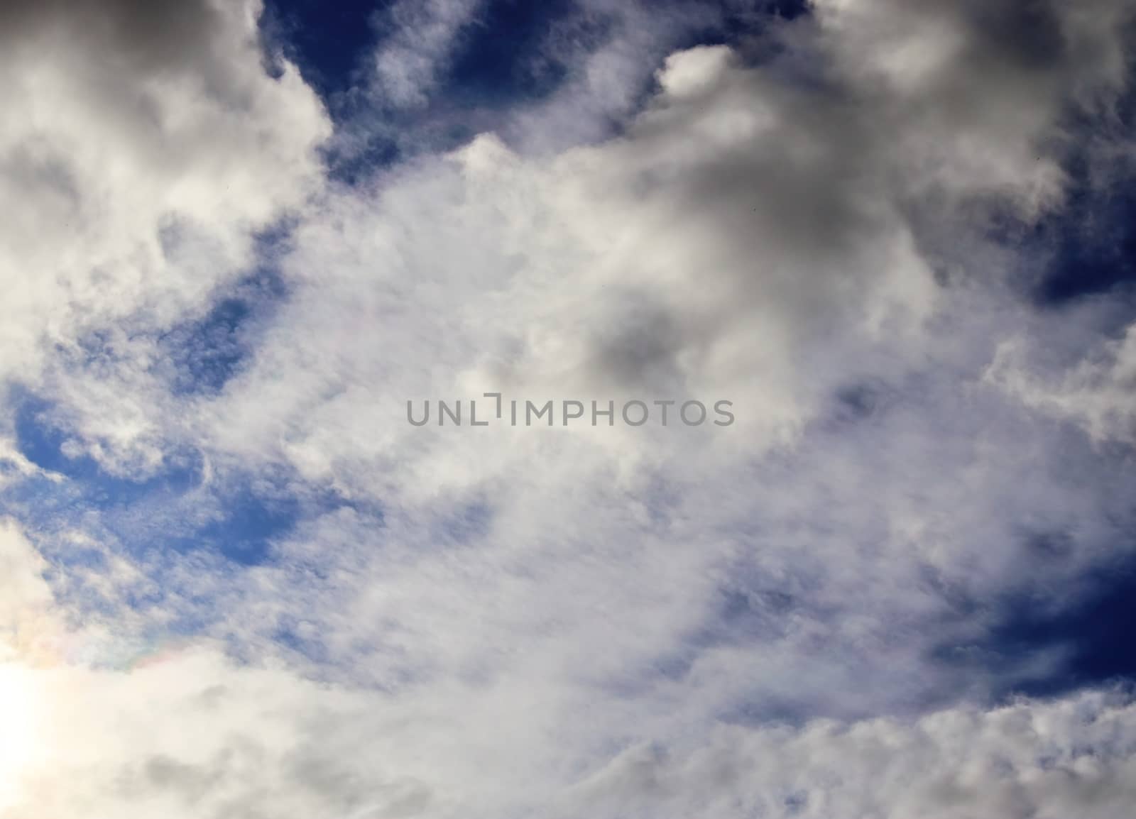 Beautiful view at bright sunbeams with some lens flares and clouds in a blue sky