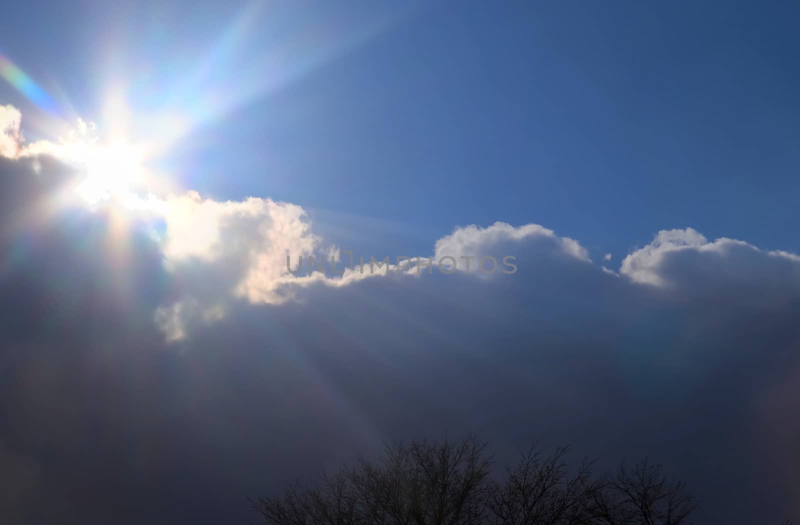 Beautiful view at bright sunbeams with some lens flares and clouds in a blue sky