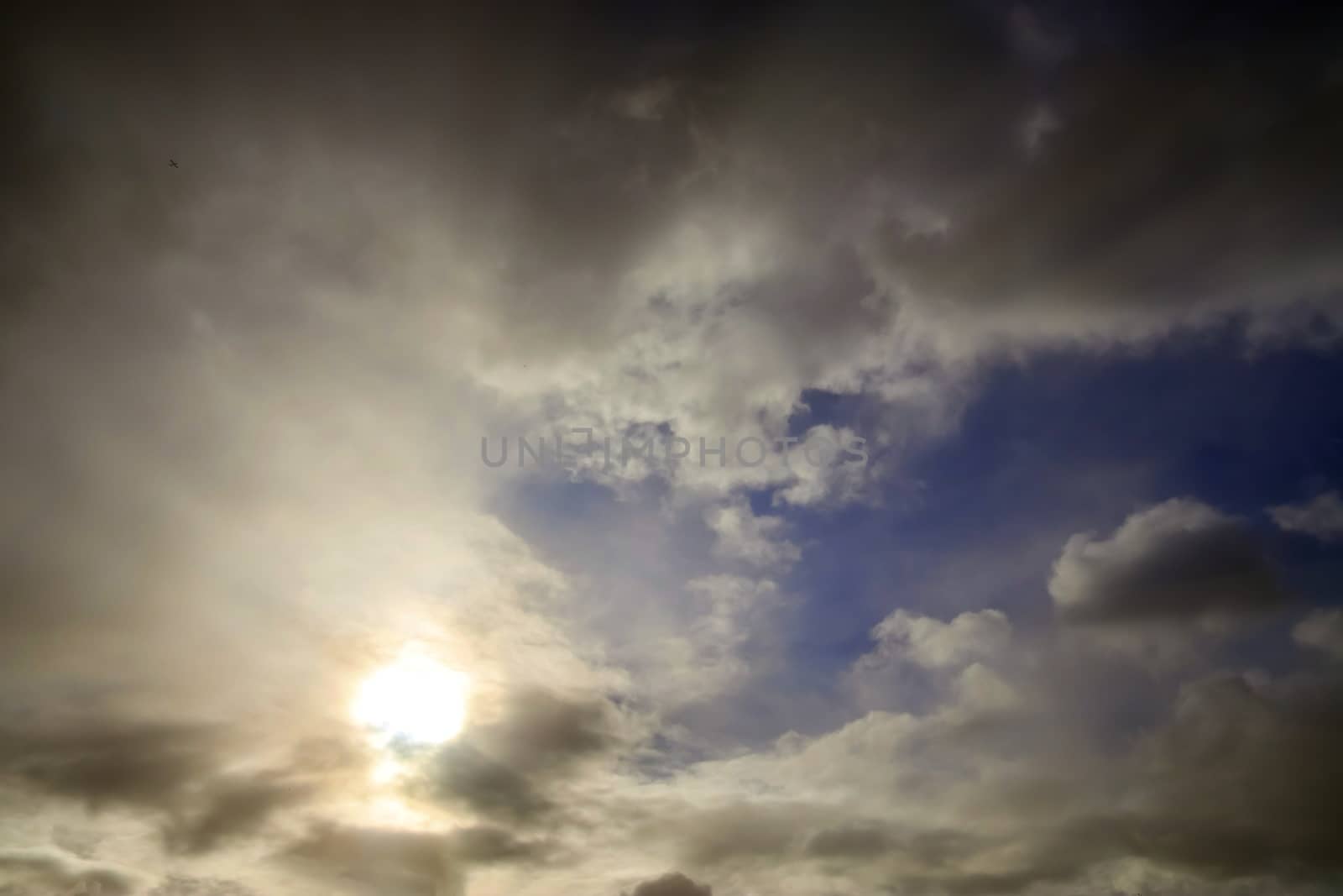 Beautiful view at bright sunbeams with some lens flares and clouds in a blue sky