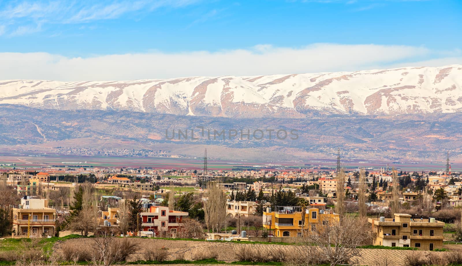 Lebanese houses in Beqaa Valley with snow cap mountains in the b by ambeon