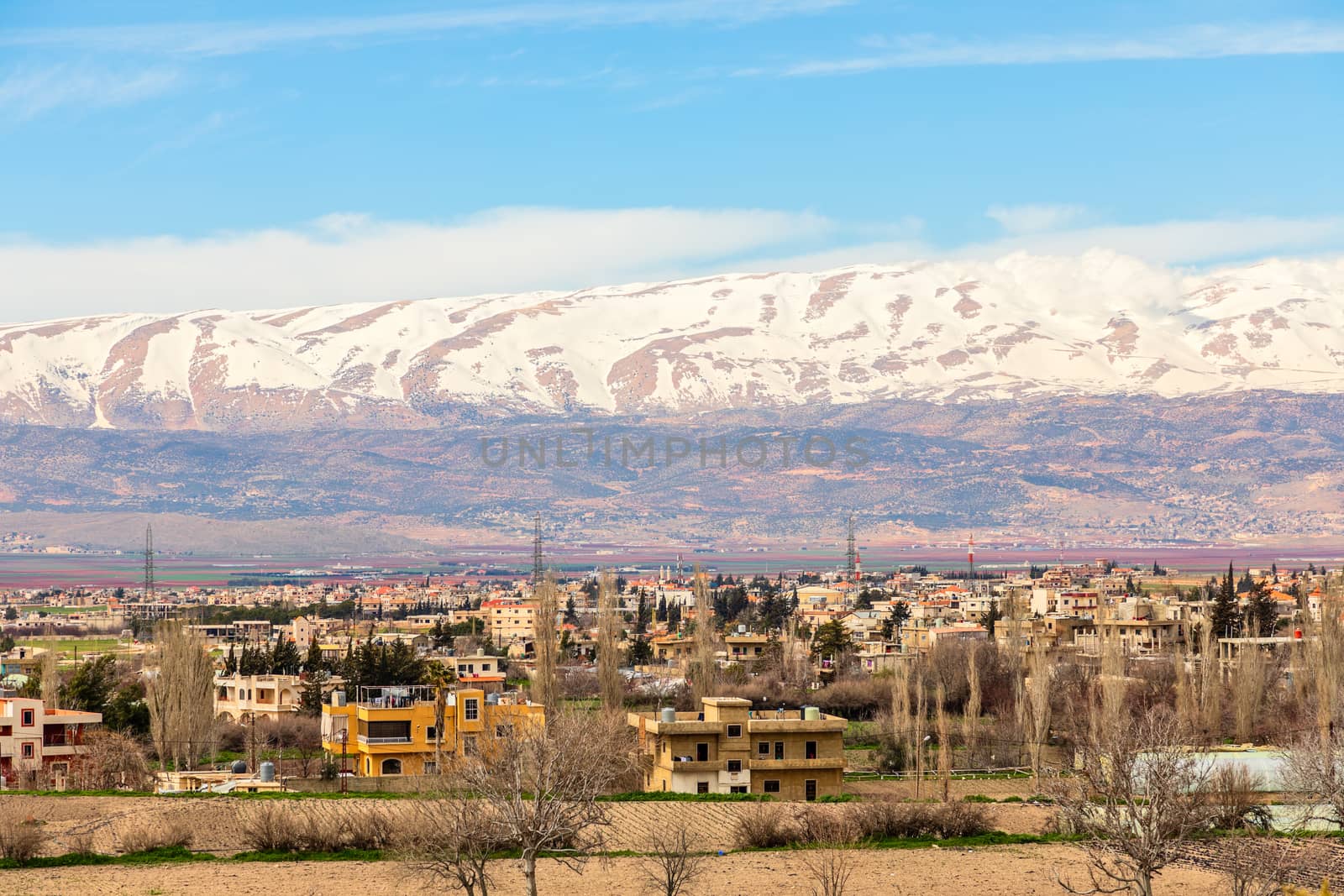 Lebanese houses in Beqaa Valley with snow cap mountains in the b by ambeon