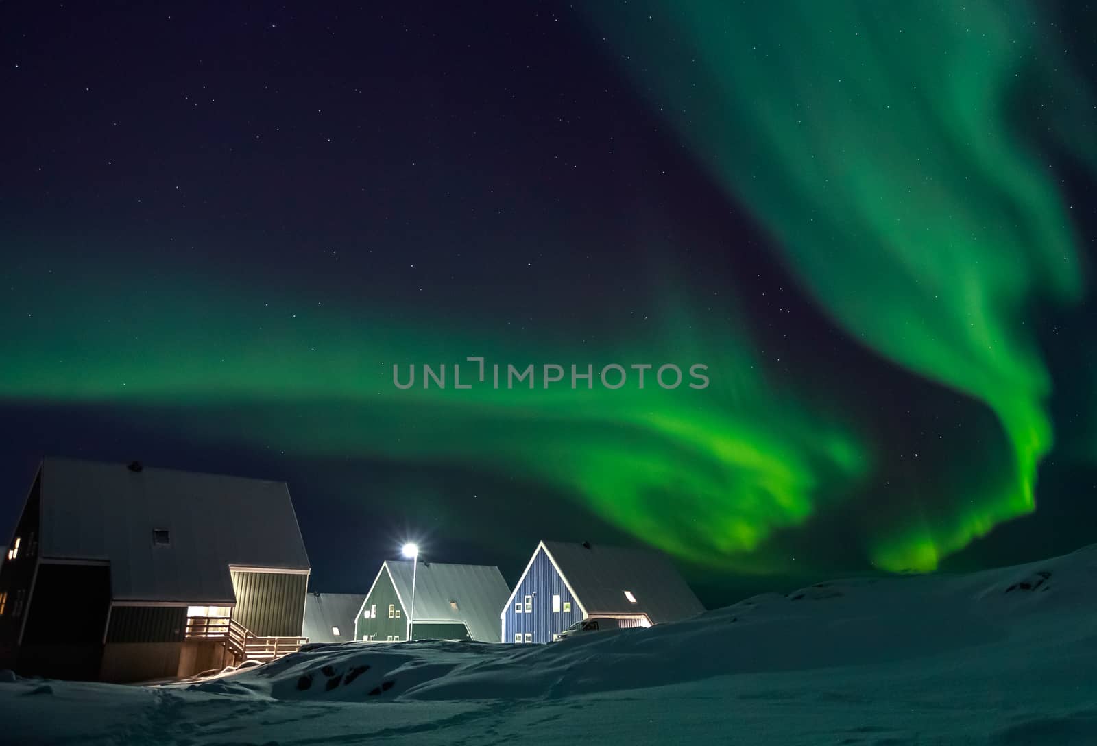 Arctic village and green waves of Northern lights over Inuit houses, in a suburb of Nuuk, Greenland