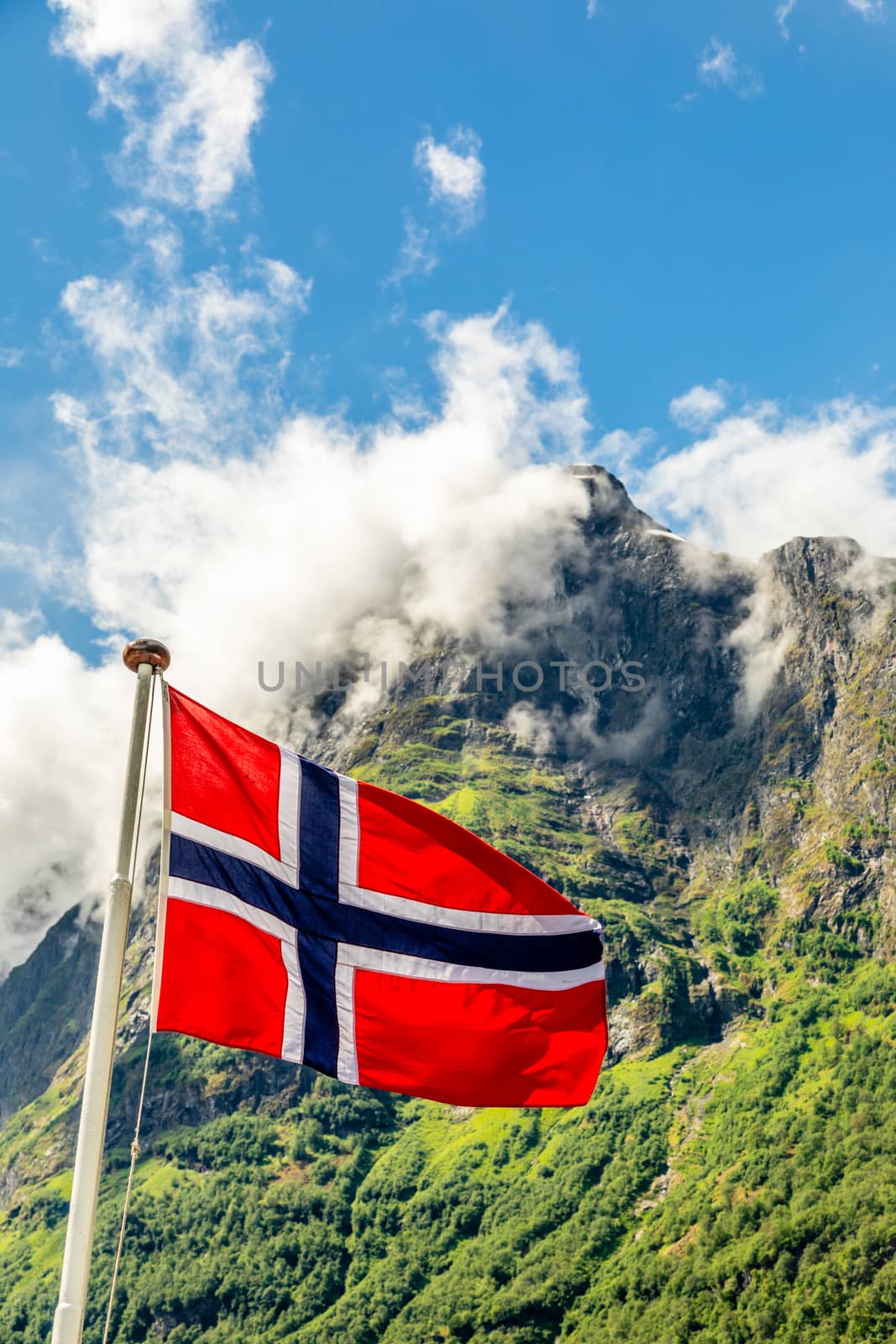 Norwegian national flag waving in the wind and mountain's peak i by ambeon