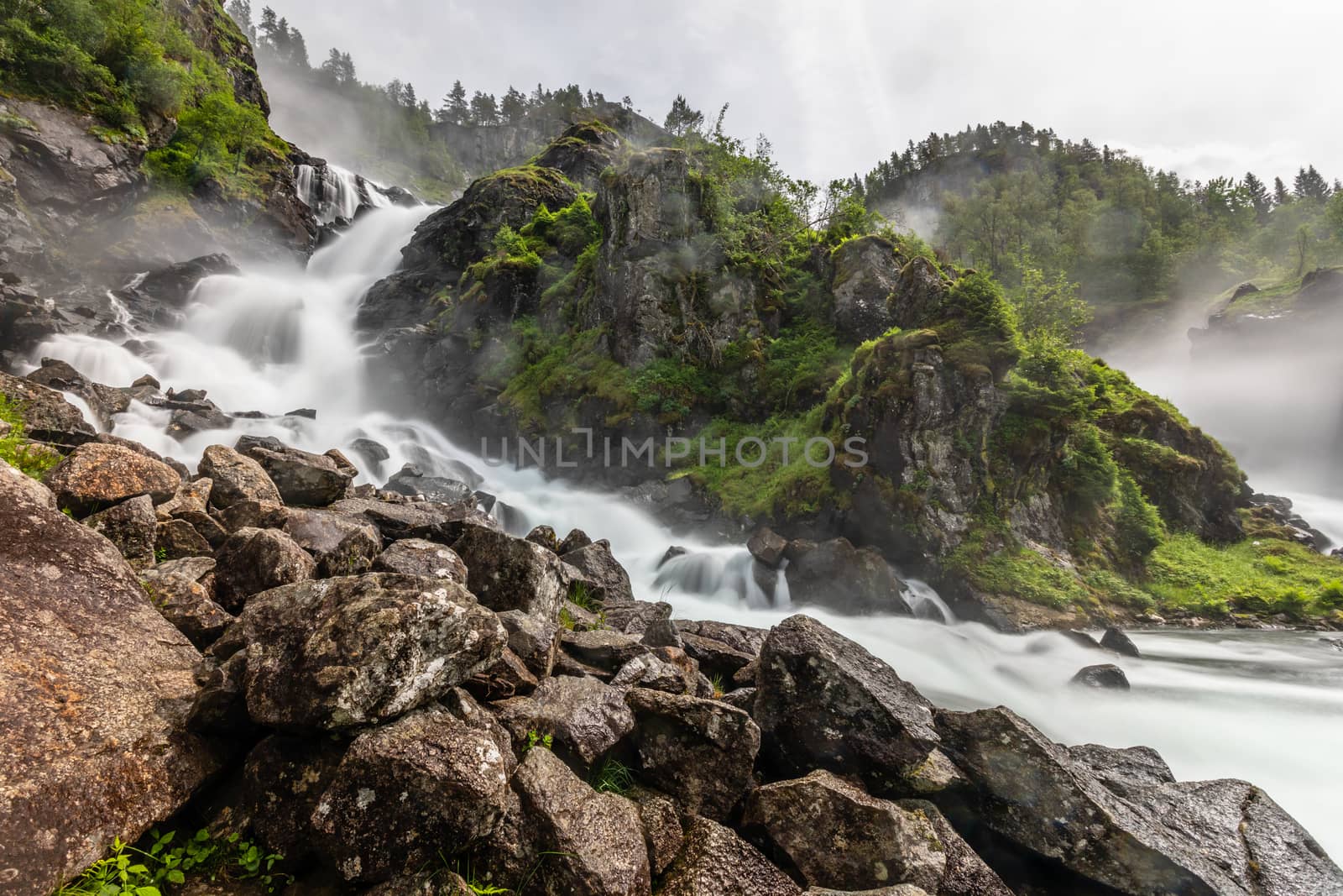 Latefoss waterfalls streams with stones in the foreground, Odda, Hordaland county, Norway