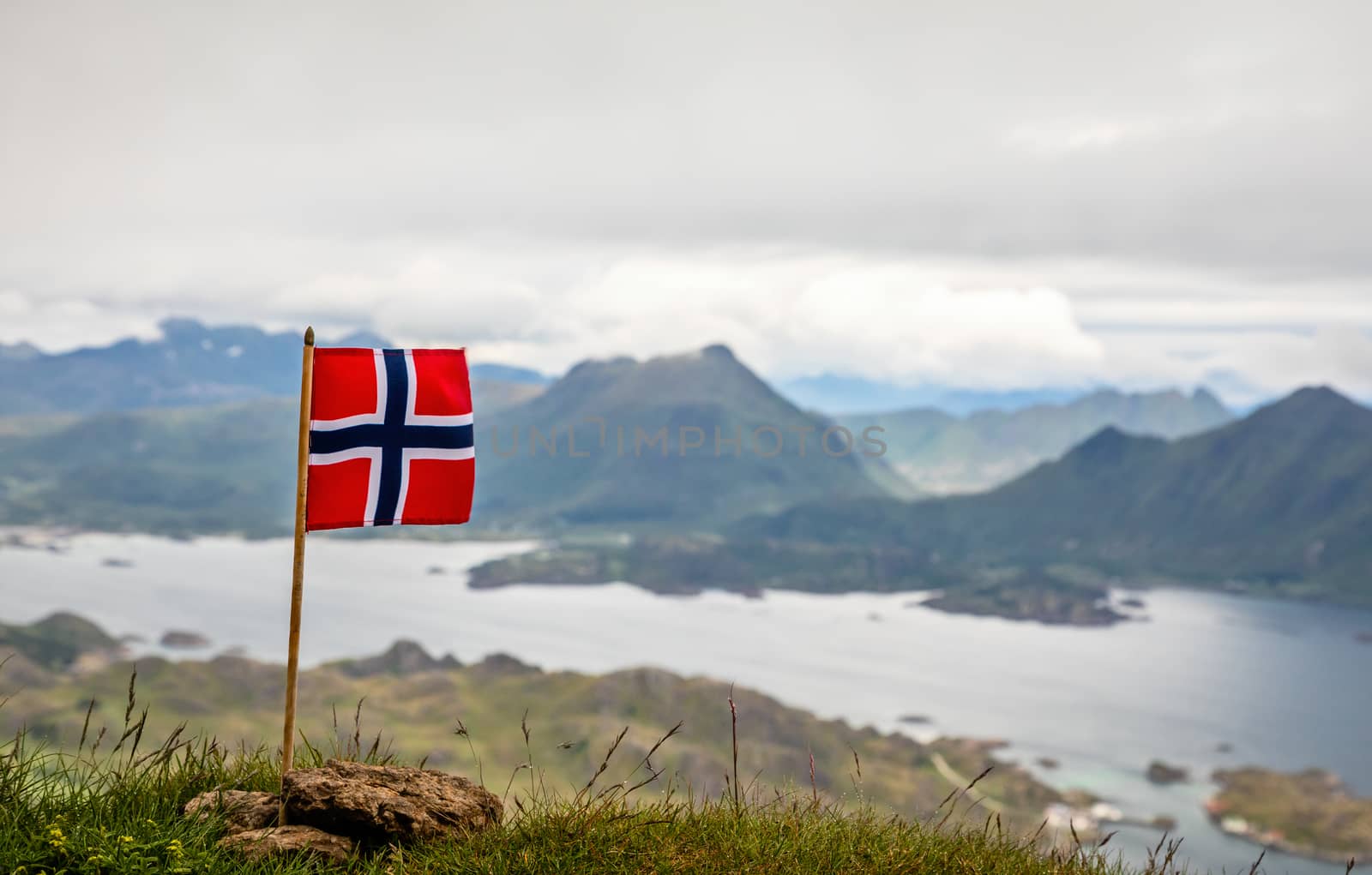 Norwegian national flag in the wind on the top of Nonstinden pea by ambeon