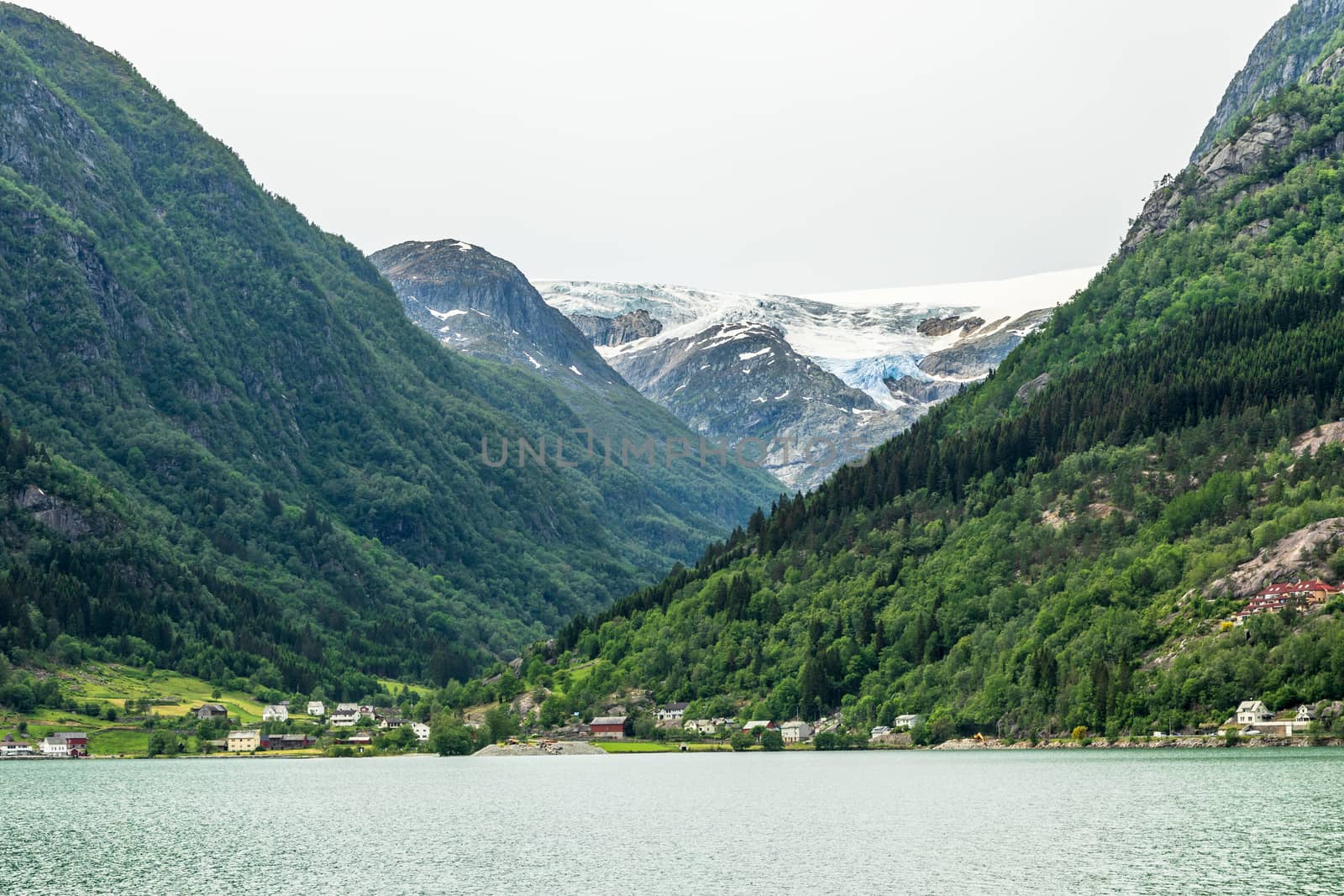 Folgefonna glacier cap in the mountains with lake and village in the foreground, Odda, Hardanger region,  Hordaland county, Norway