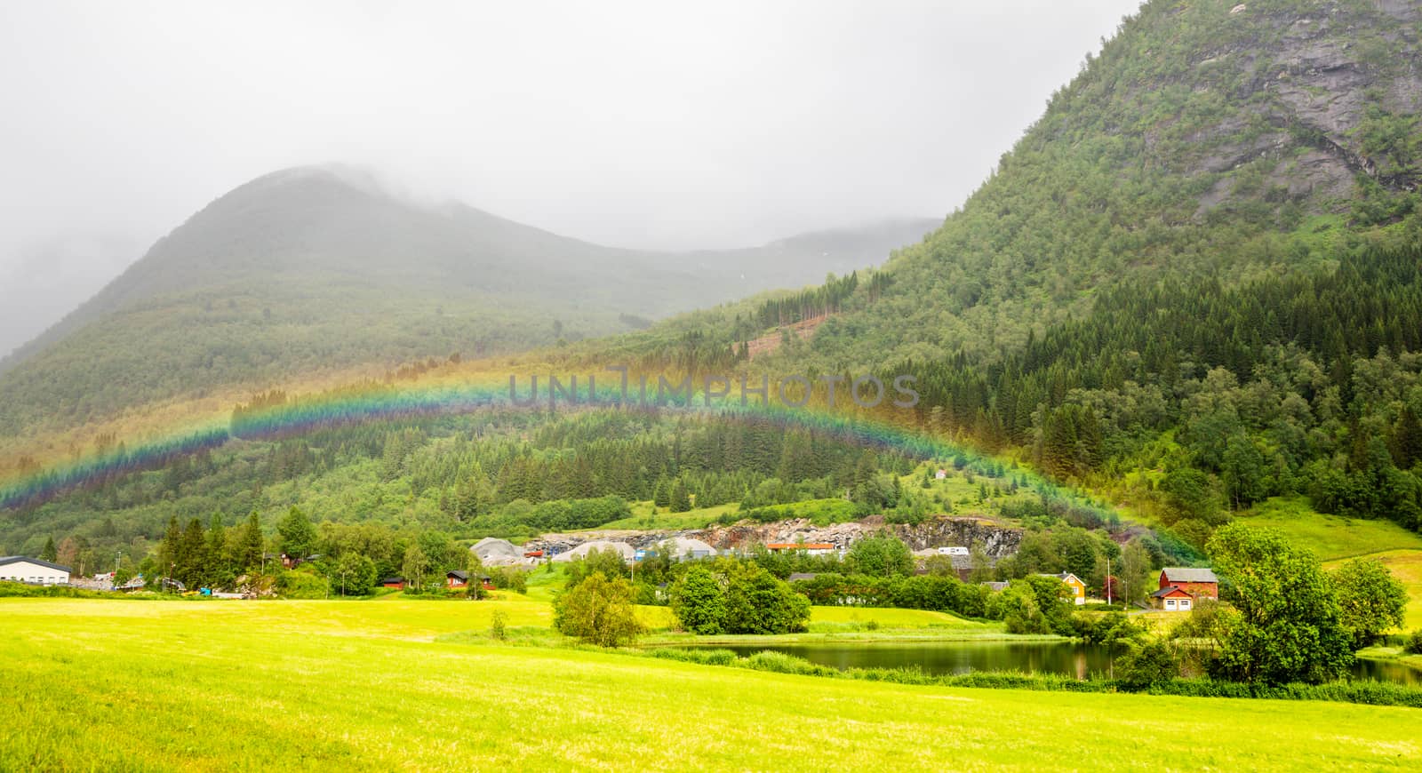 Colorful rainbow over the fields, lake and houses of Skei village, Jølster in Sogn og Fjordane county, Norway.