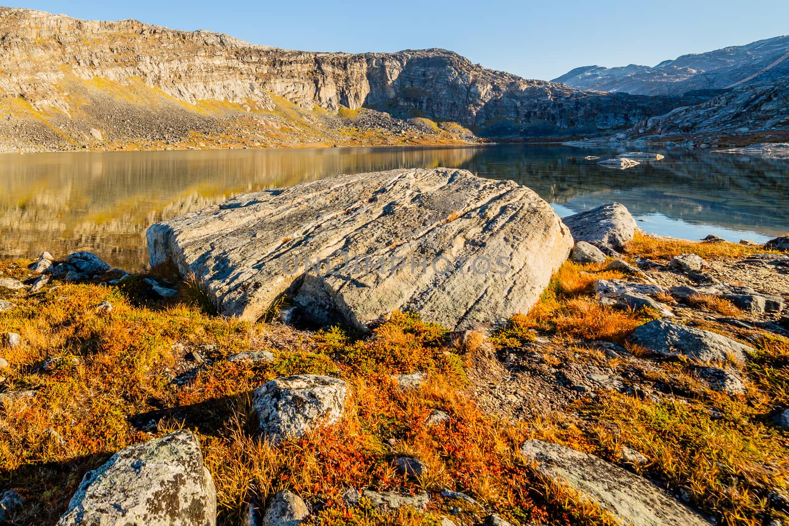 Orange autumn greenlandic  tundra landscape with big stone and lake in the background, Nuuk, Greenland