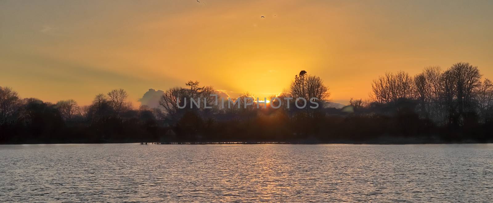 Beautiful and romantic sunset at a lake in stunning yellow and orange colors