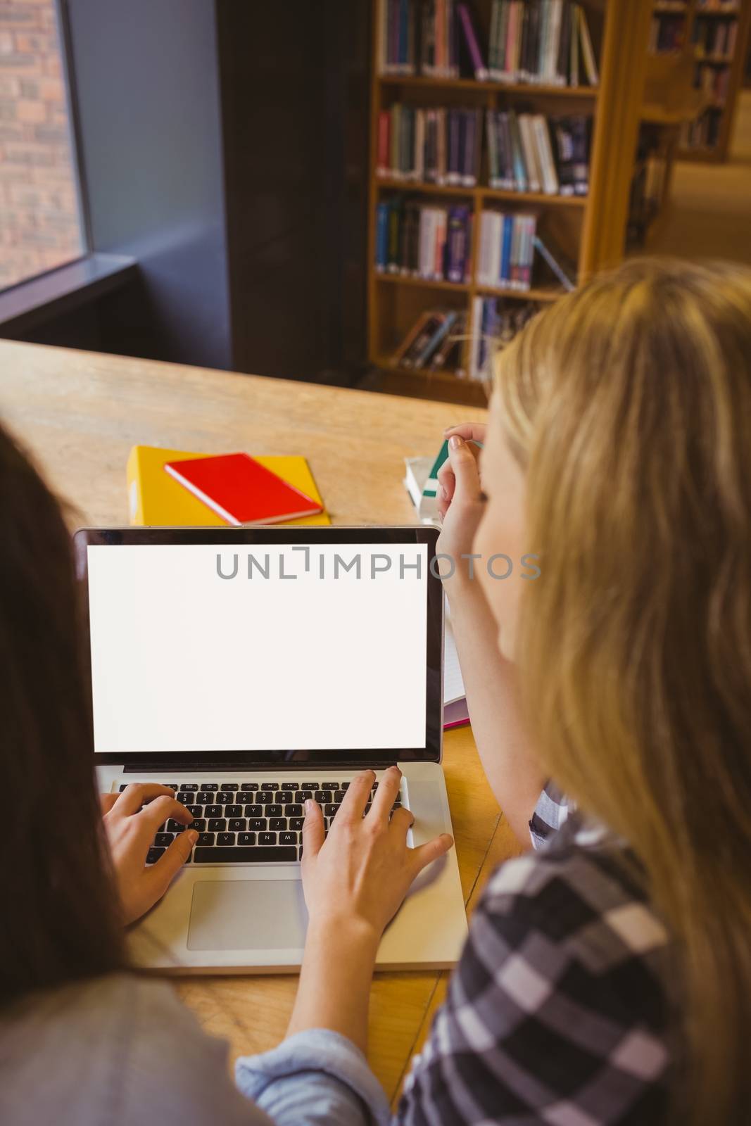 Rear view of students using laptop  by Wavebreakmedia