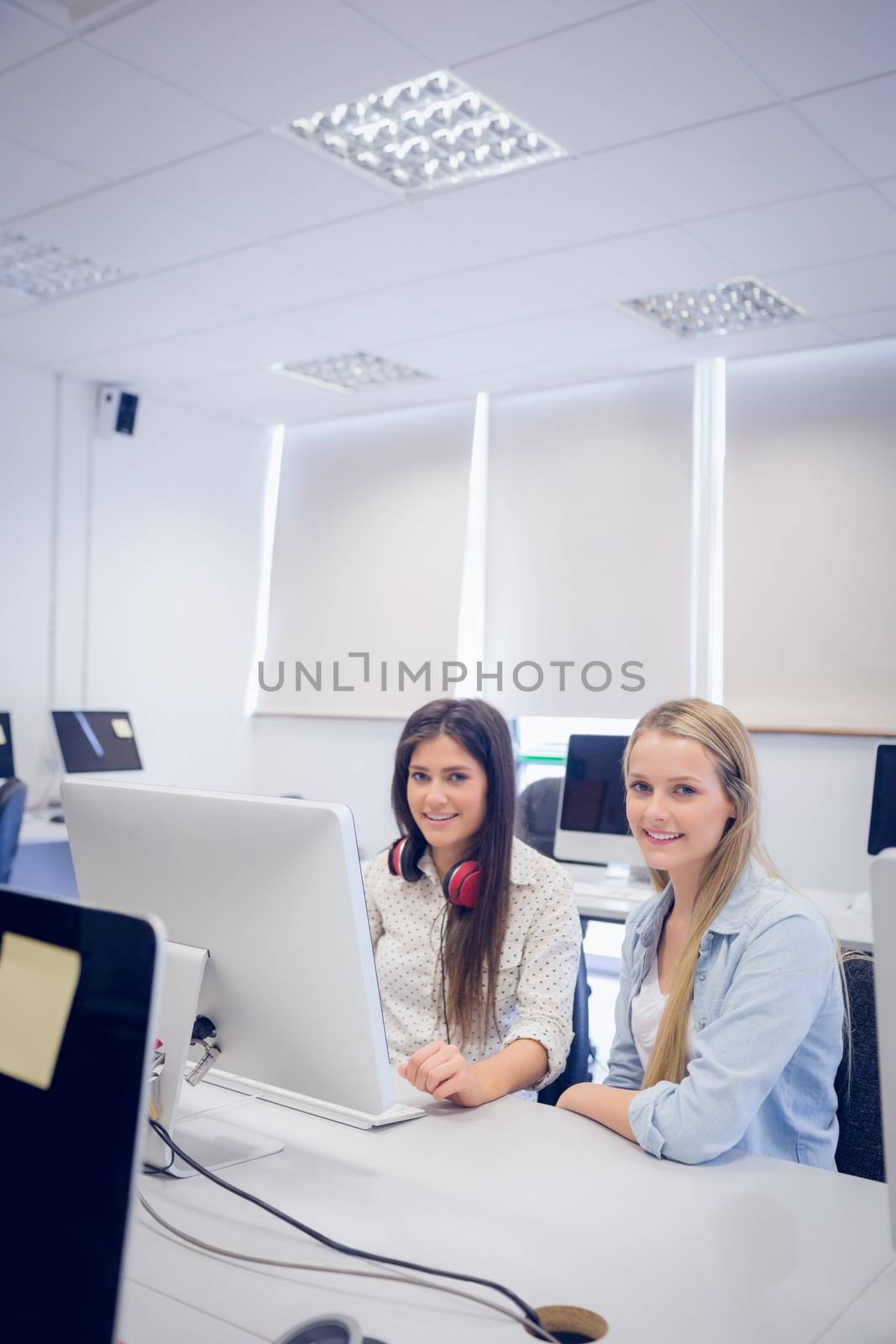Smiling students using computer at university 