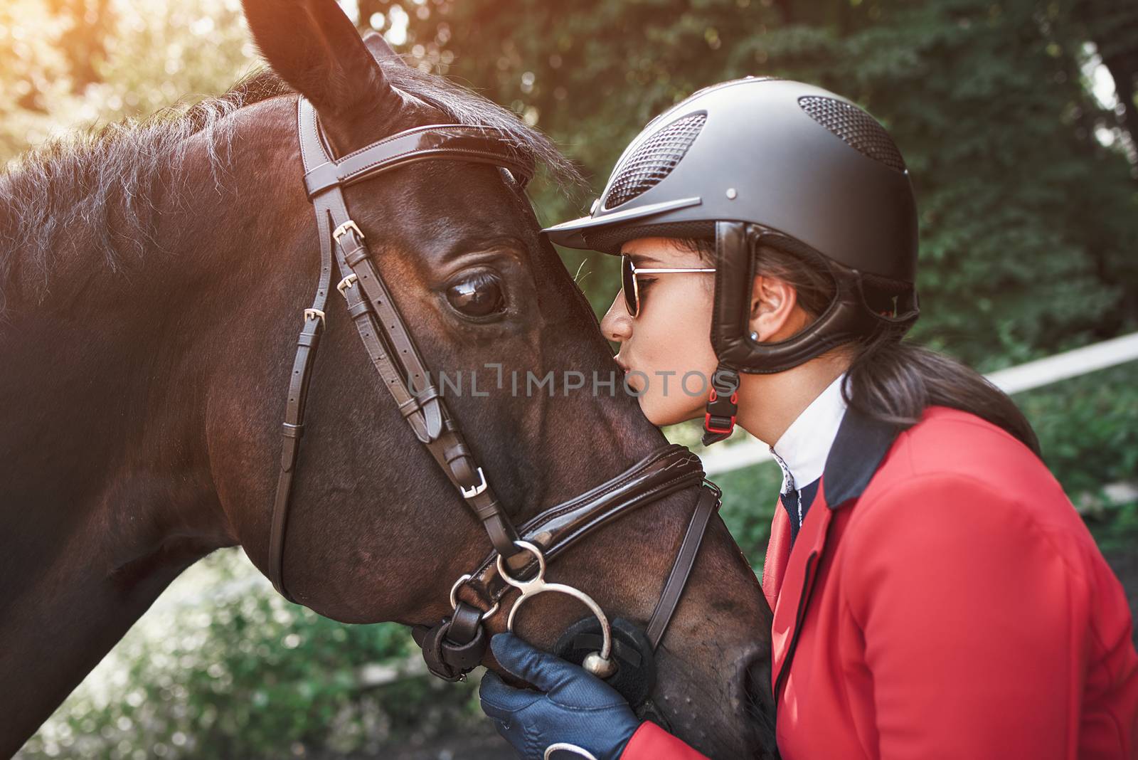 A young girl talking and kissing her horse. She loves the animals and joyfully spends her time in their environment.