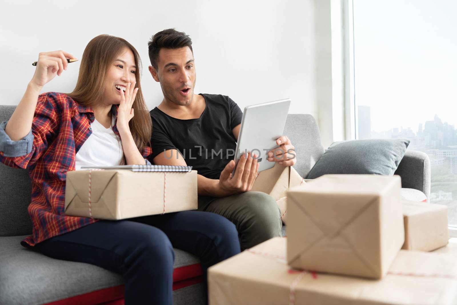 Successful of Young couple are celebrating with profits of their small business online. Male and Female are looking to digital tablet computer at the house together. Achieving goals.