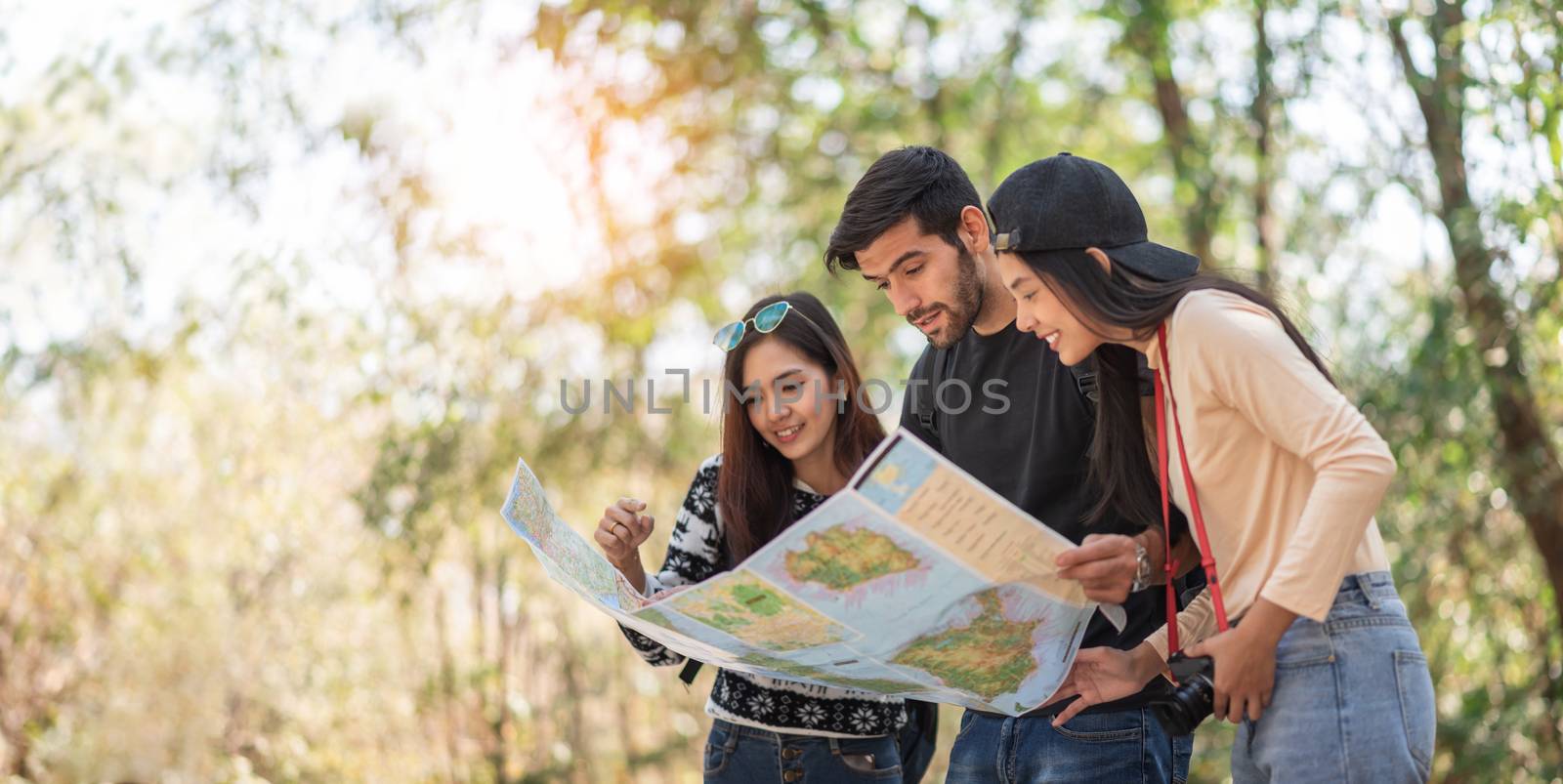 Multi-Ethnic Travelers looking at the map on travel vacations wi by Aekkarak