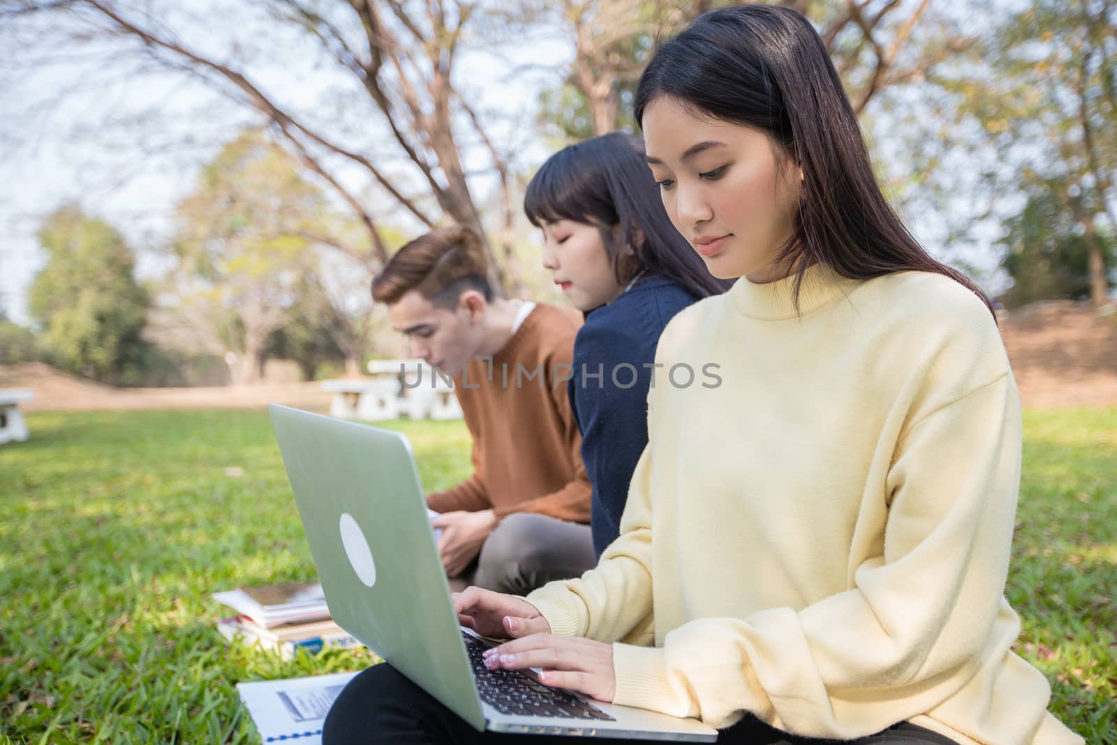 Asian students use notebook computers and tablet to work and study online in garden at home during the coronavirus epidemic and quarantine at home