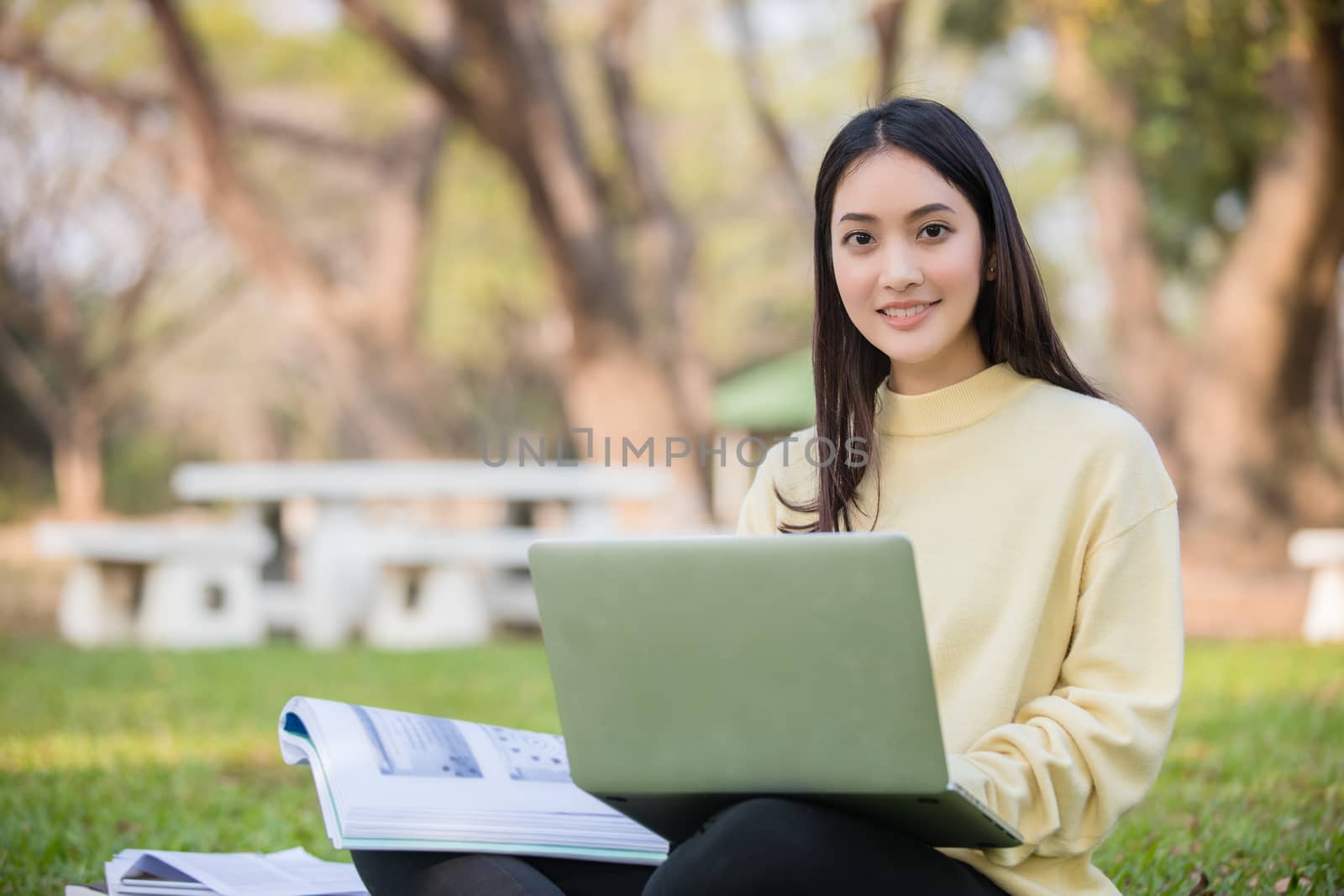 Asian students use notebook computers and tablet to work and study online in garden at home during the coronavirus epidemic and quarantine at home