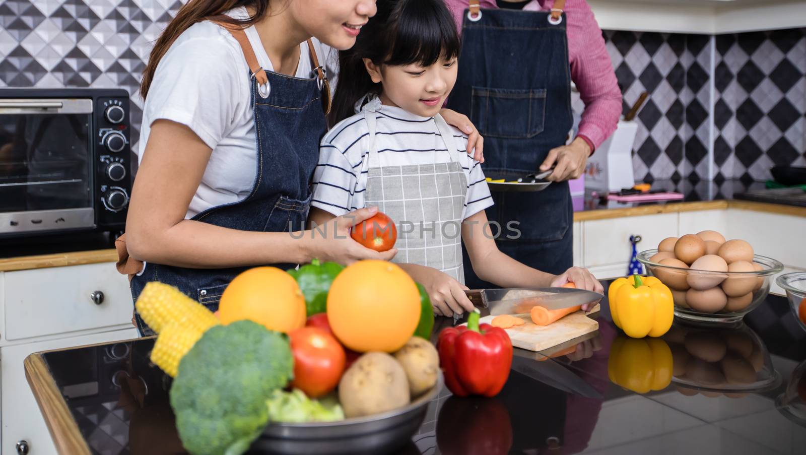 Asian families are cooking  and parents are teaching their daughters to cook in the kitchen at home. 
Family activities on holidays and Happy in recreation concept