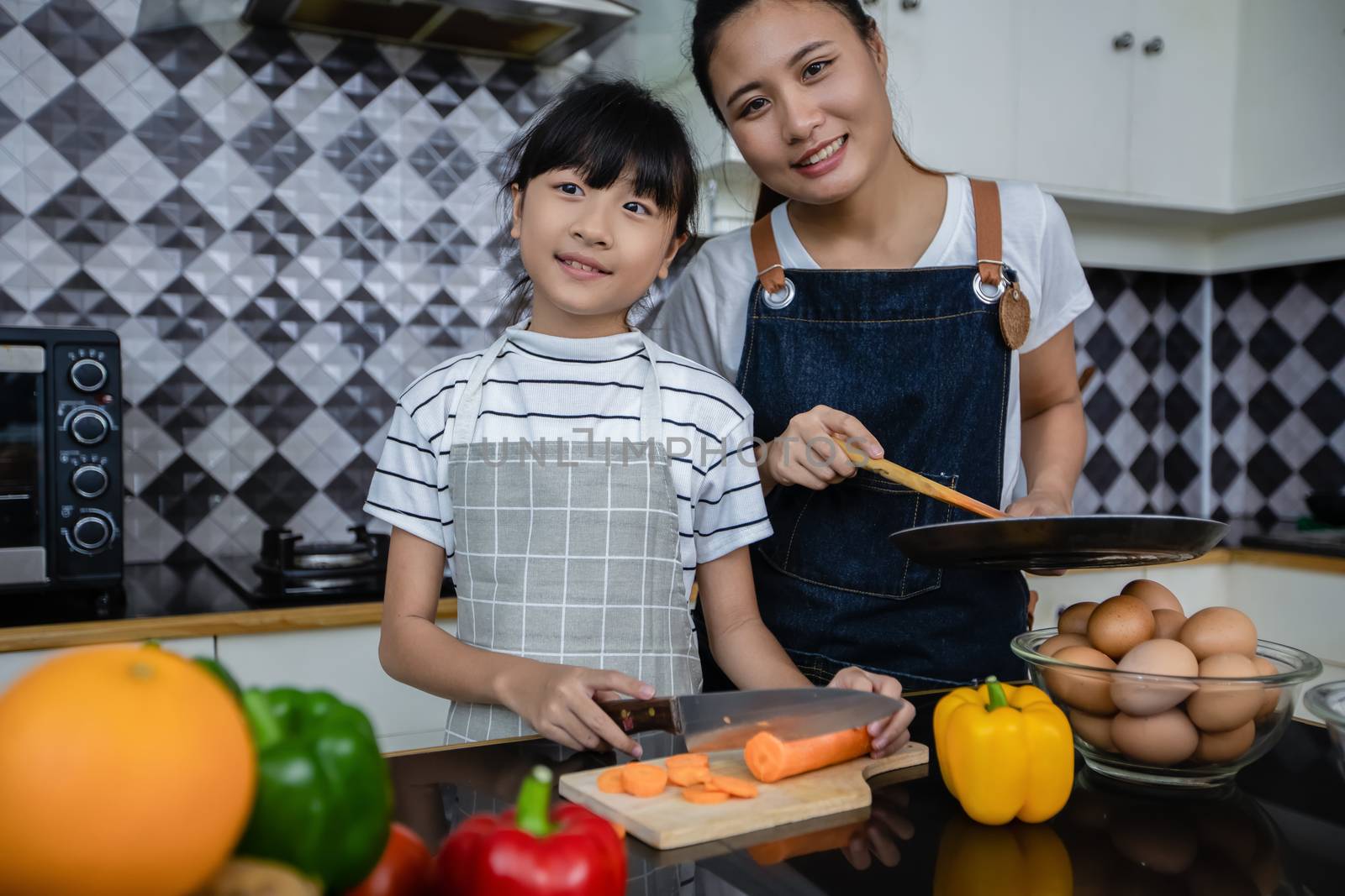 Asian families are cooking  and parents are teaching their daughters to cook in the kitchen at home.  Family activities on holidays and Happy in recreation concept by Tuiphotoengineer