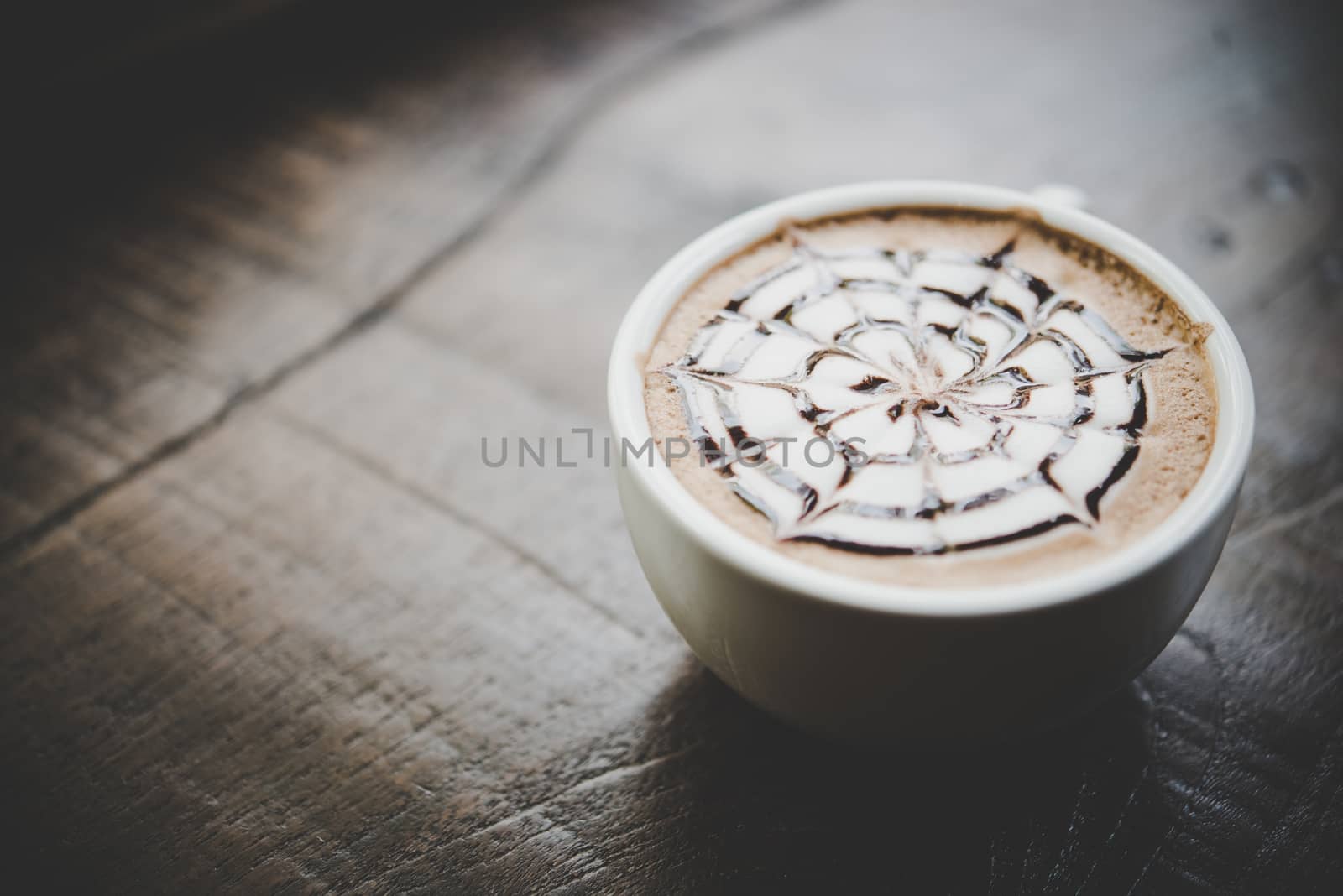 A cup of coffee on wooden table in cafe.