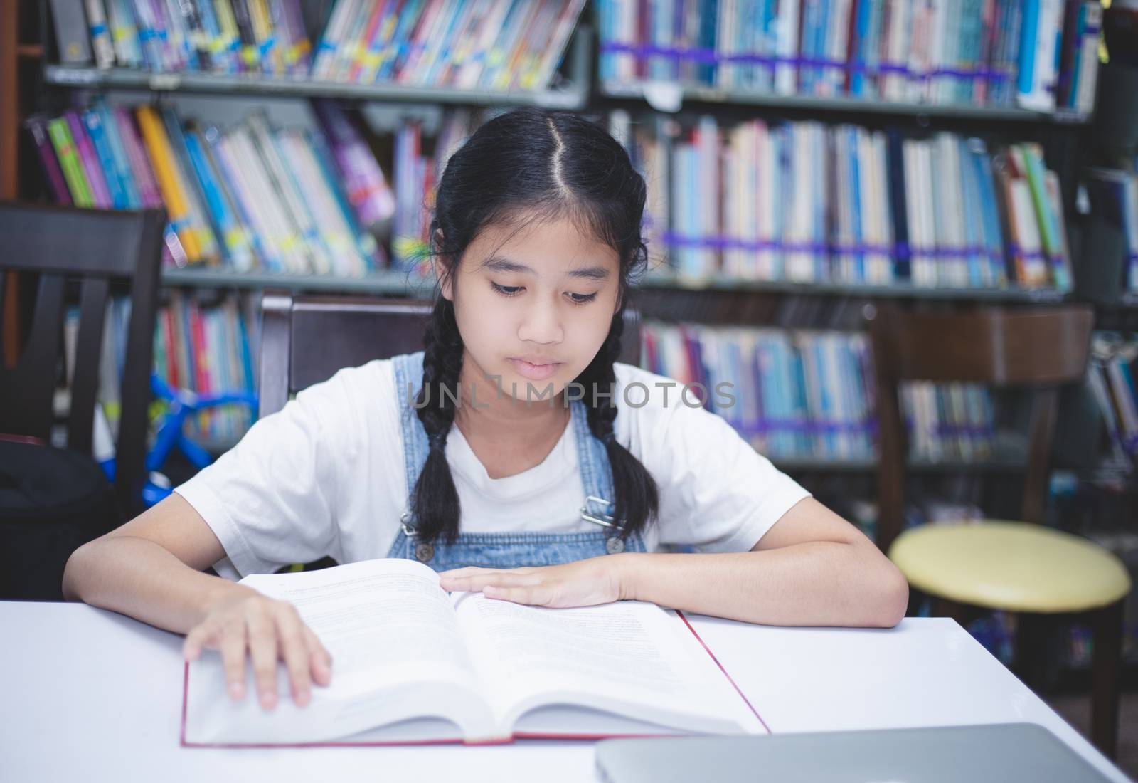 Asian girl students reading books and using notebook in the library.