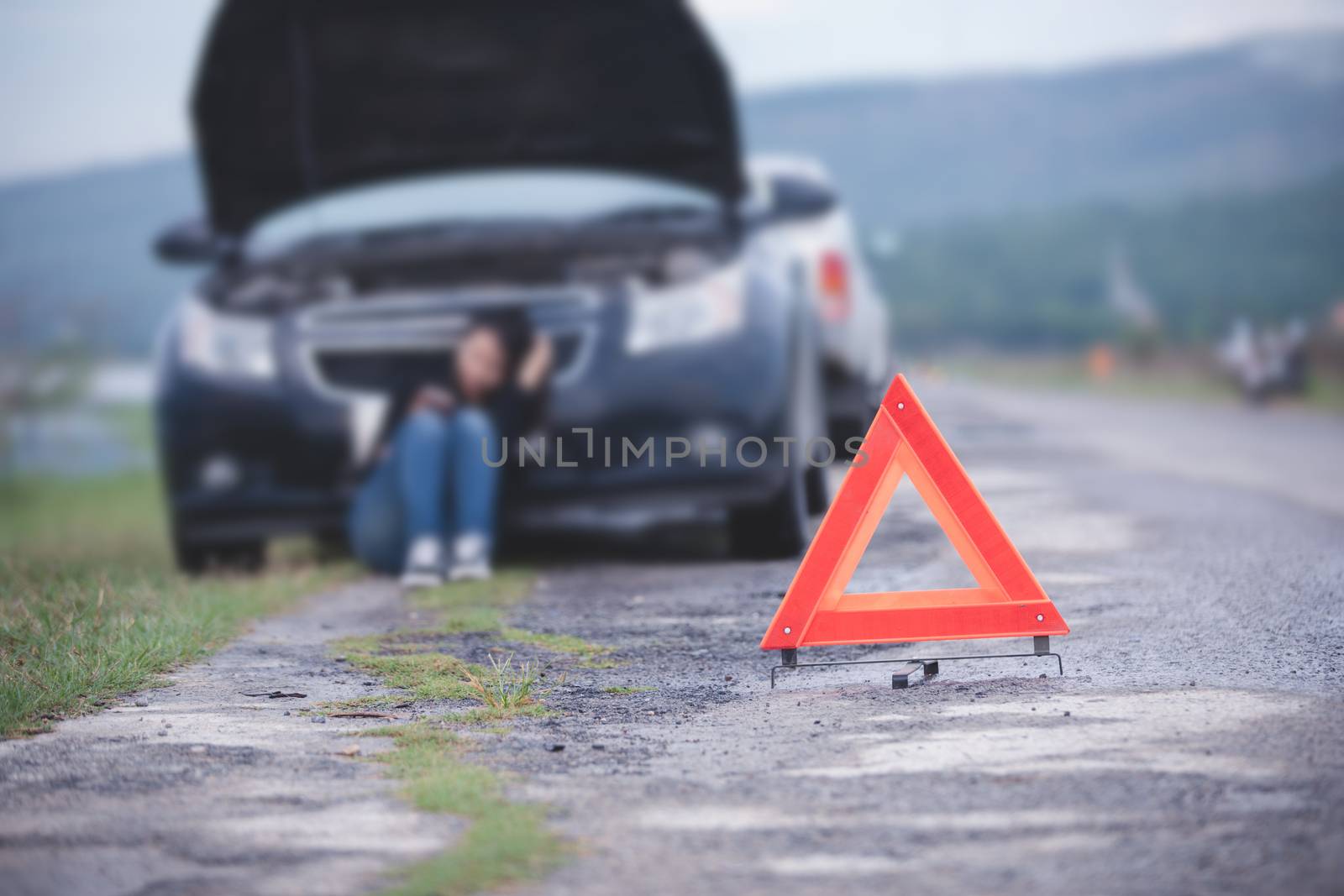 Asian woman sitting on floor near broken down car with Red trian by Tuiphotoengineer