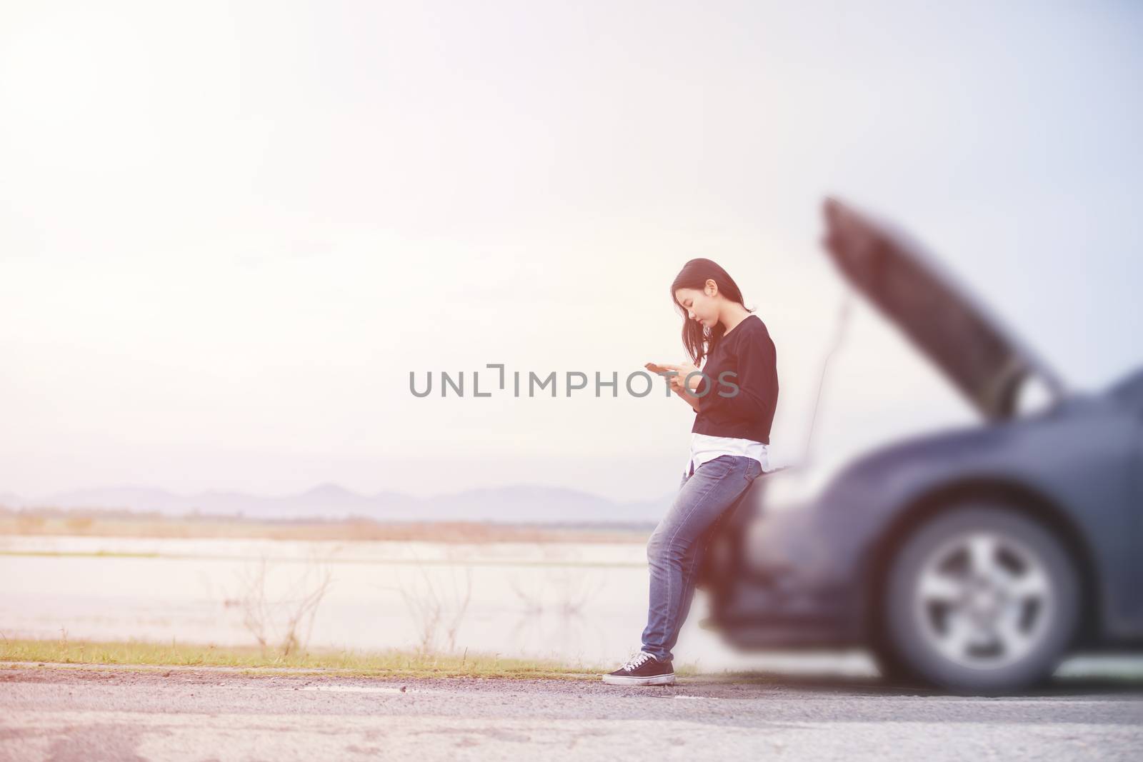 Asian woman is using a telephone to call the car mechanic. For f by Tuiphotoengineer