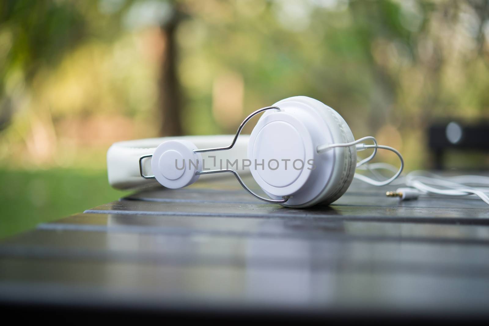 Mobile phone with headphone on wooden table with nature background - Vintage Filter.