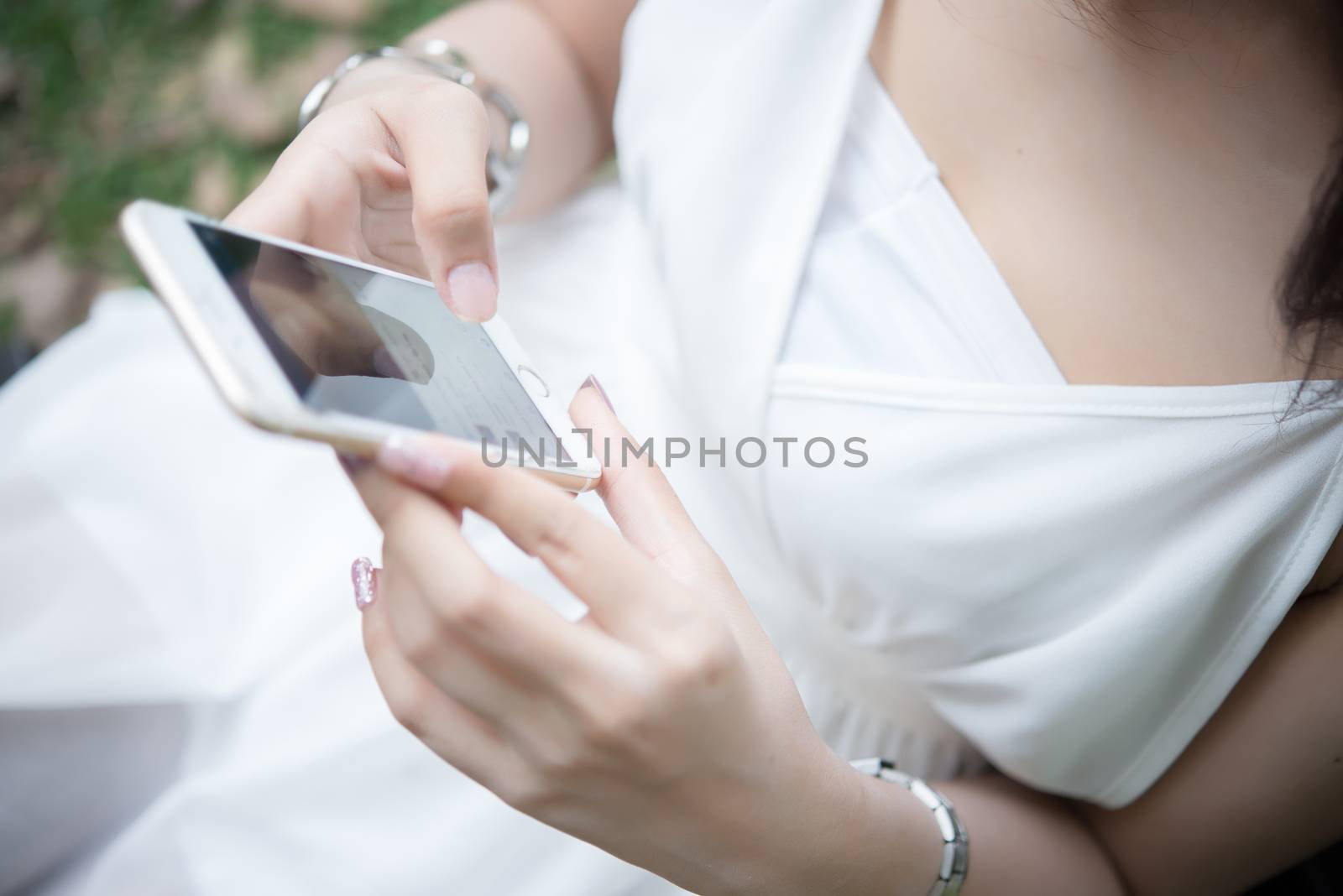 Girl sitting with a tablet in hands. Young relaxing at park with her tablet. Women lifestyle concept.