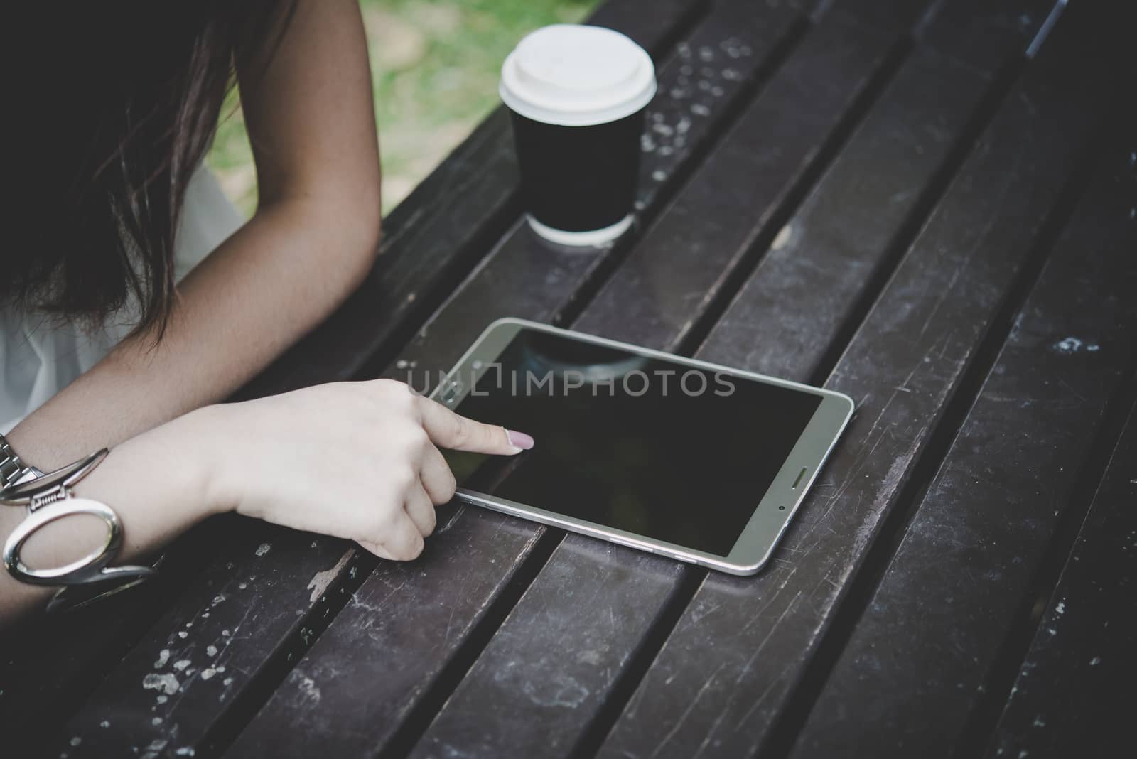 Close up of woman hands holding tablet computer on the wooden table with cup of coffee.