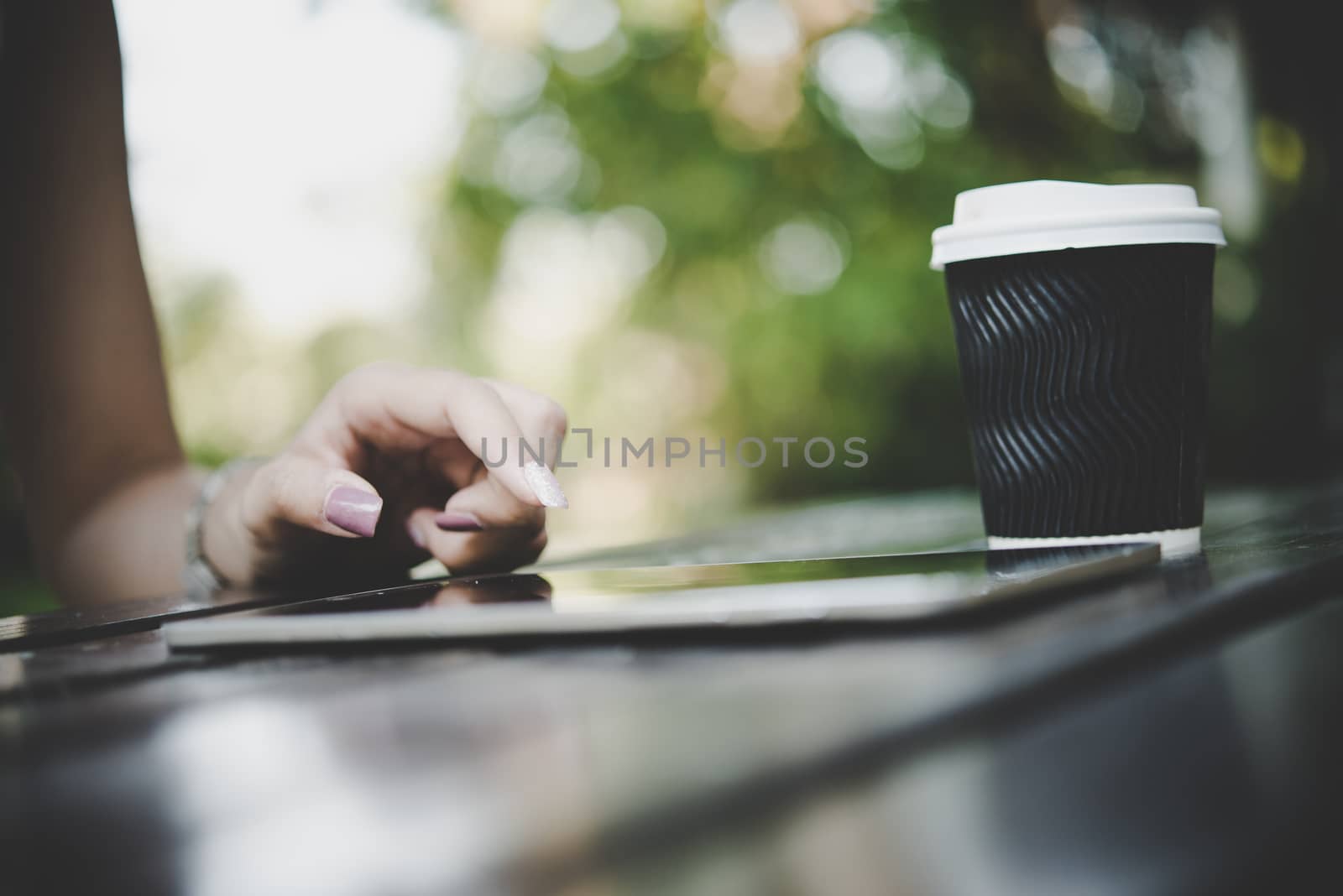 Close up of woman hands holding tablet computer on the wooden table with cup of coffee.