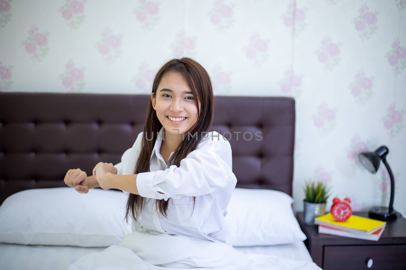 Asian woman Beautiful young smiling woman sitting on bed and stretching in the morning at bedroom after waking up in her bed fully rested