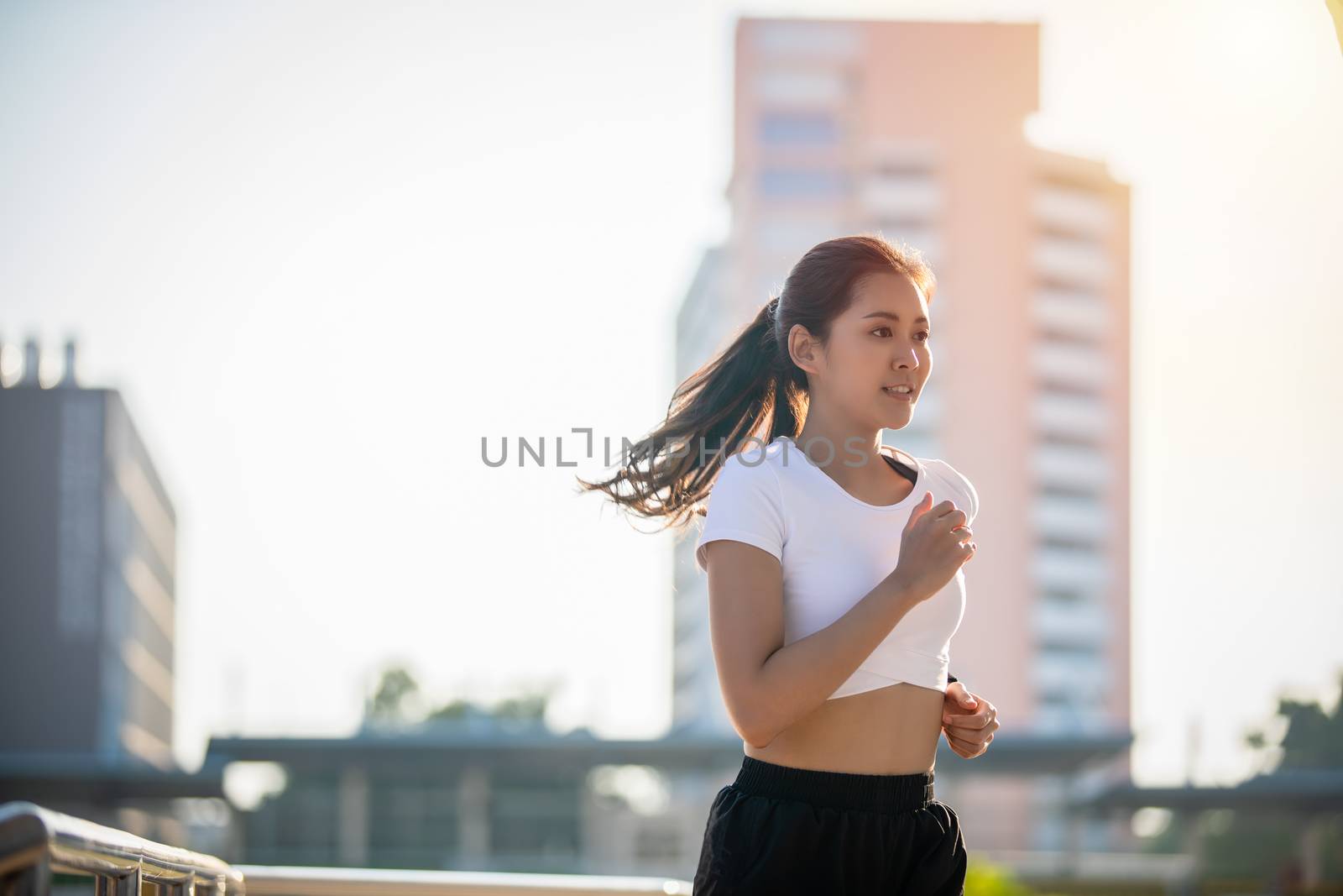 Asian Young fitness sport woman running  and smiling on city road