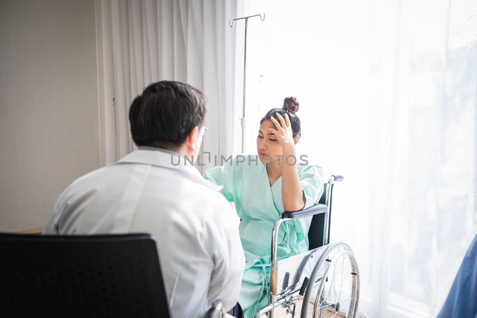 The doctors are asking and explaining about the illness to a female patient lying in bed at a hospital.