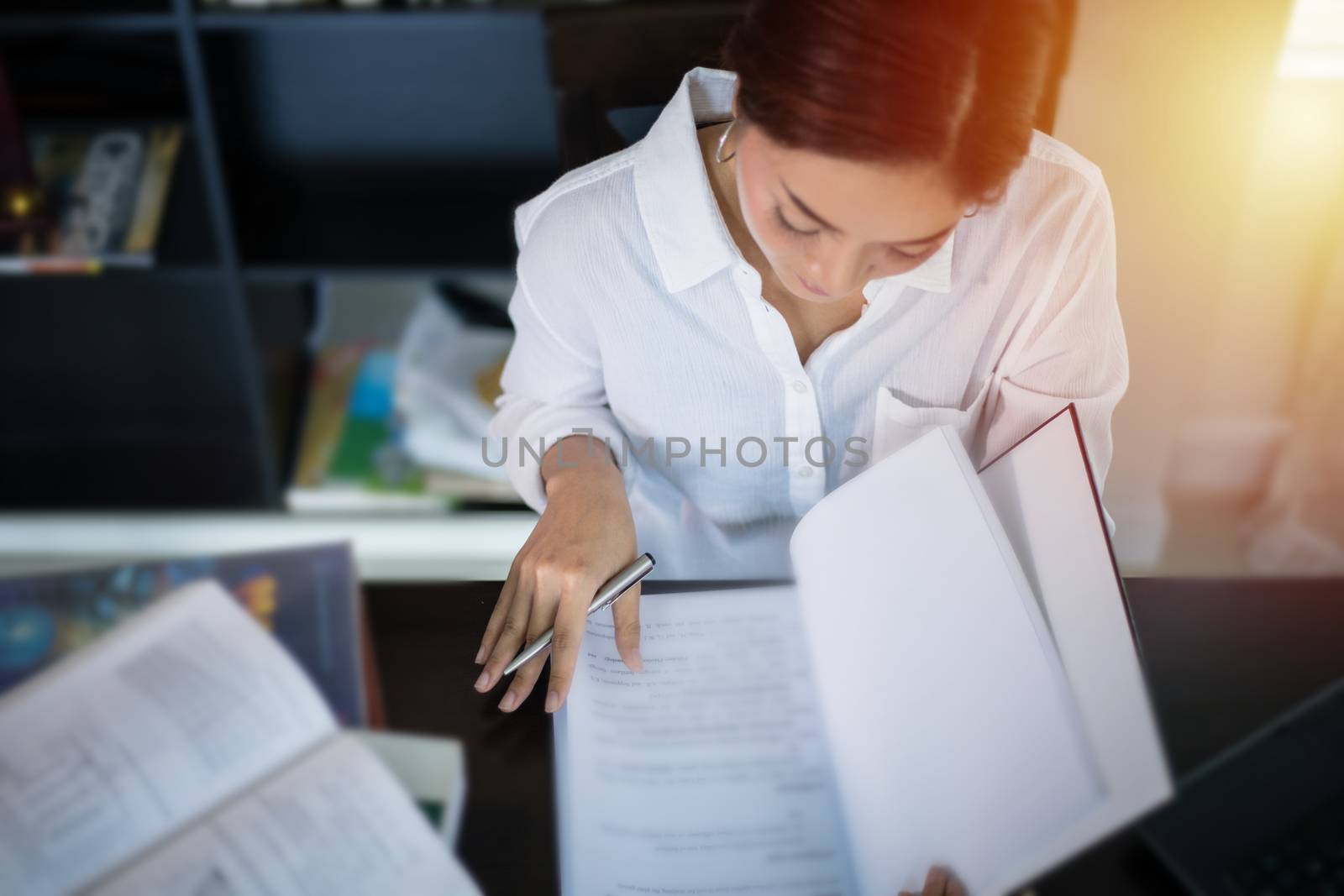Asian women student smiling and reading a book for final exam at home