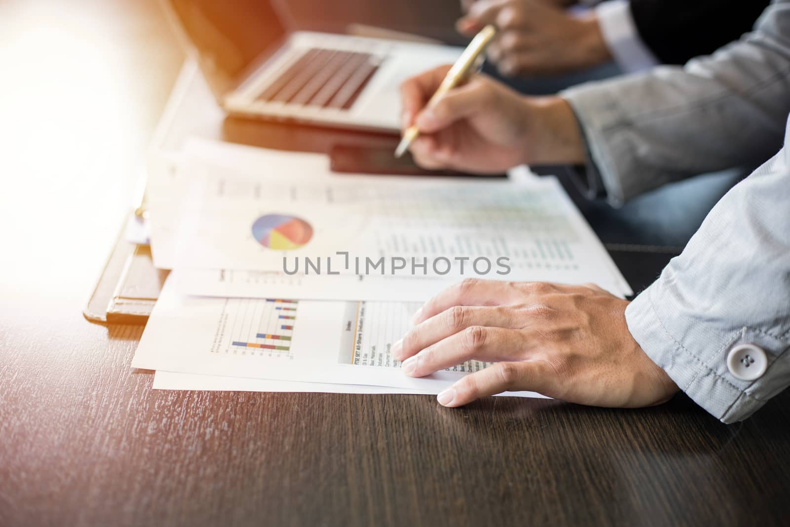 Asian businesswomen holding a pen and analysis documents on office table with laptop computer and graph financial diagram working in the background