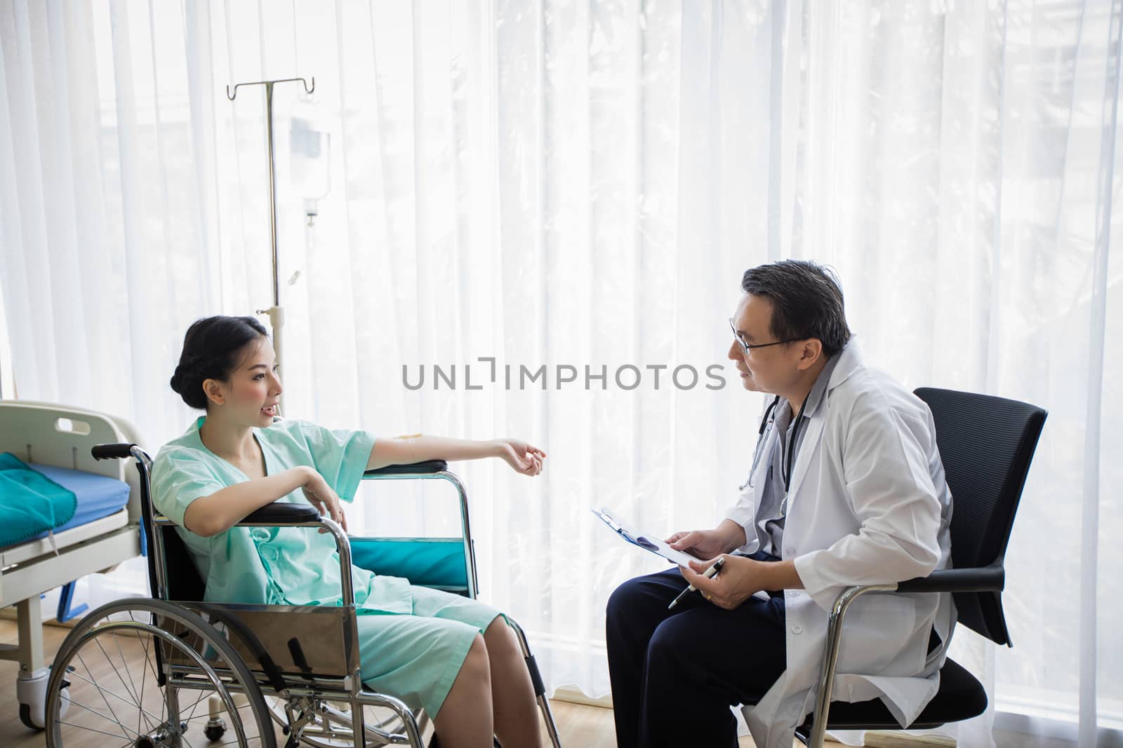 The doctors are asking and explaining about the illness to a female patient lying in bed at a hospital.