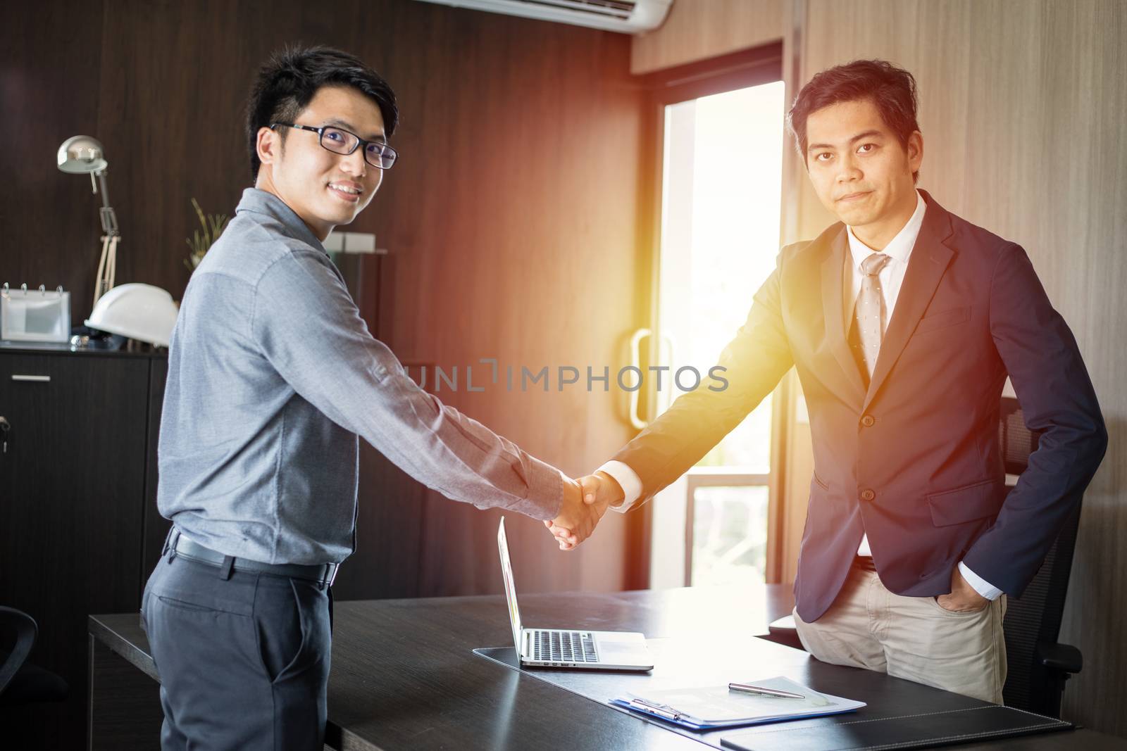 Asian Business people shaking hands and smiling their agreement to sign contract and finishing up a meeting
