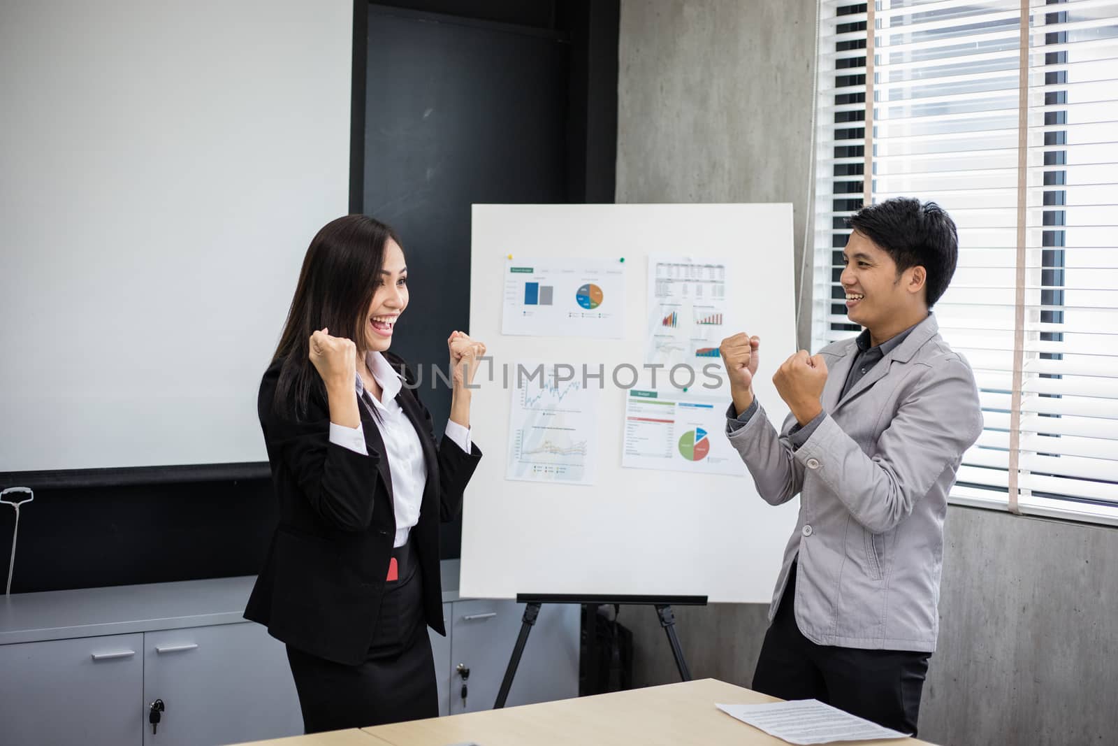Asian businessmen and businesswomen Success and winning concept - happy team with raised up hands celebrating the breakthrough and achievements