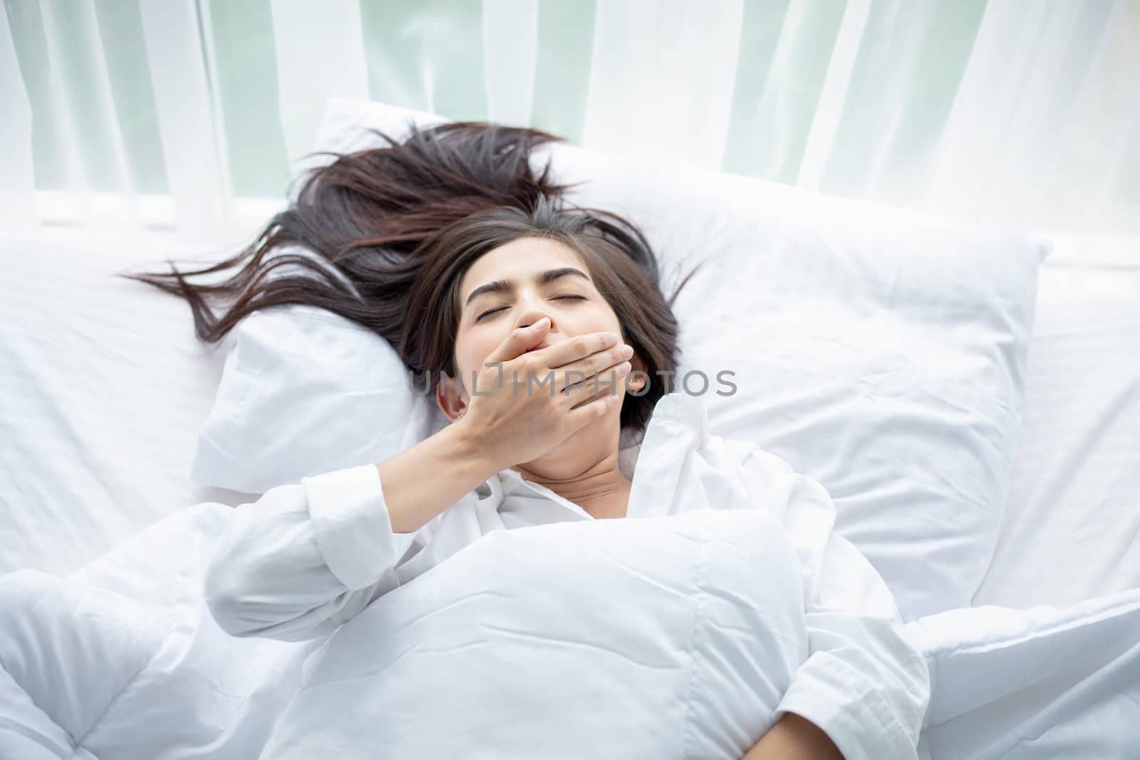 Asian woman Beautiful young smiling woman sitting and sleeping in white bed and stretching in the morning at bedroom after waking up in her bed fully rested