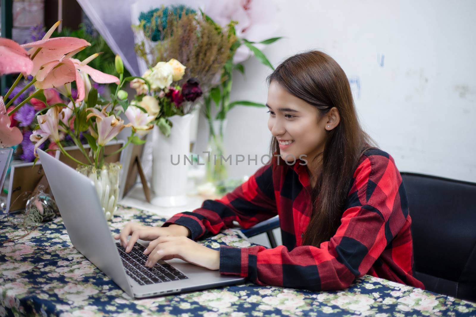 Asian women florists using notebook for working in flower shop