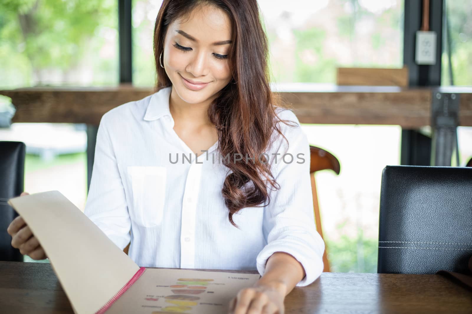 Asian woman open menu for ordering in coffee cafe and restaurant and smiling for happy time