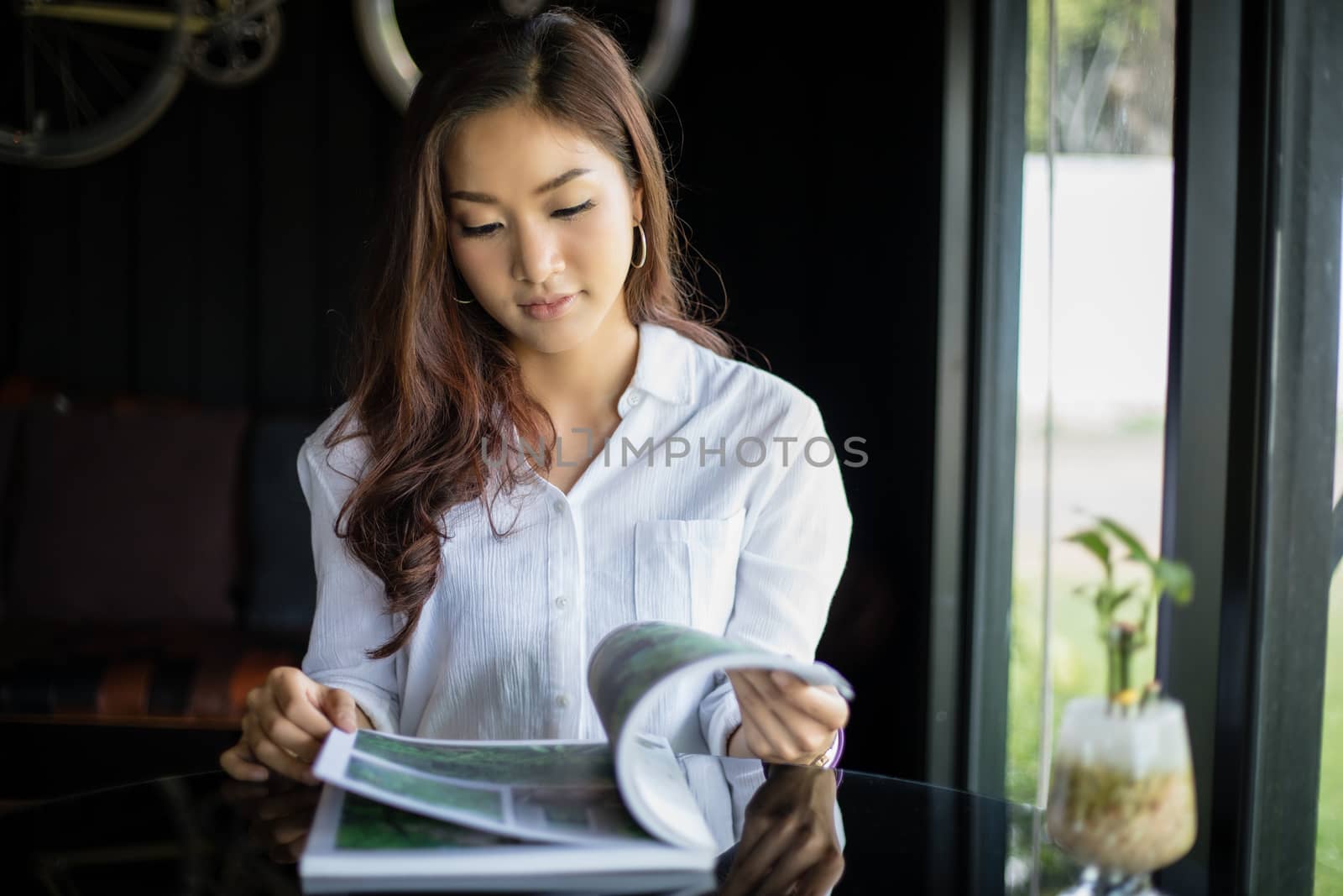 Asian women smiling and reading a book for relaxation at coffee shop