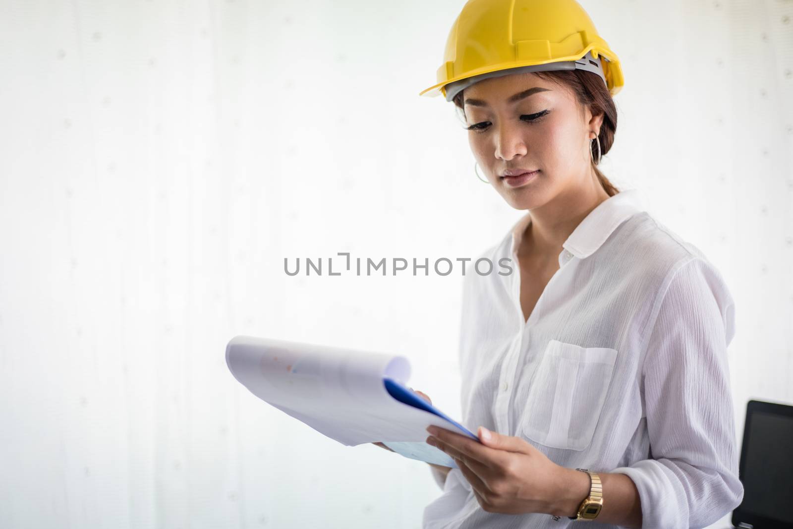 Asian women engineering inspecting and working and holding blueprints at office